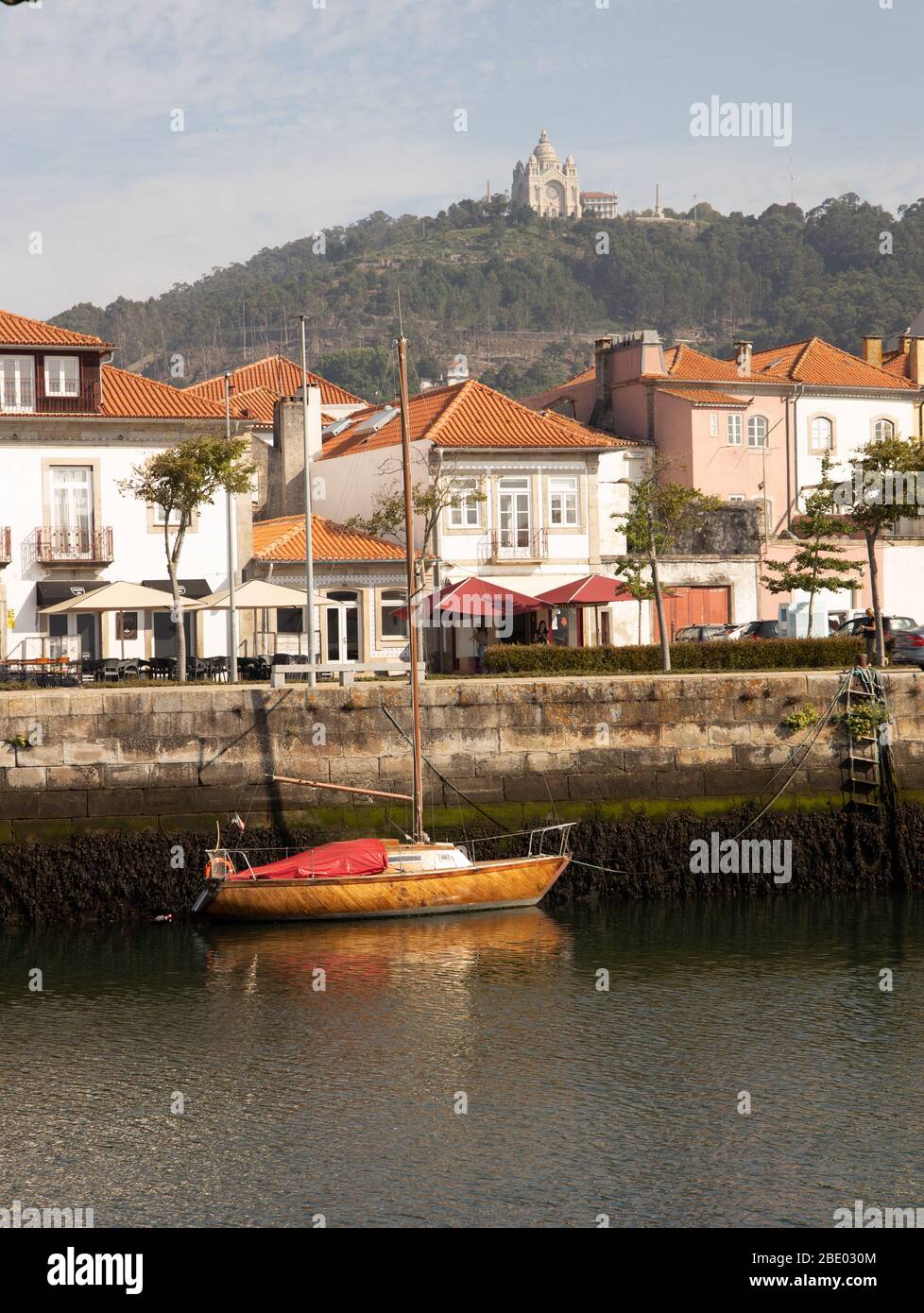 View with wooden yacht on Rio Lima waterfront and houses in Viana do Castelo with the Santuario de Santa Luzia high above the city Northern Portugal Stock Photo