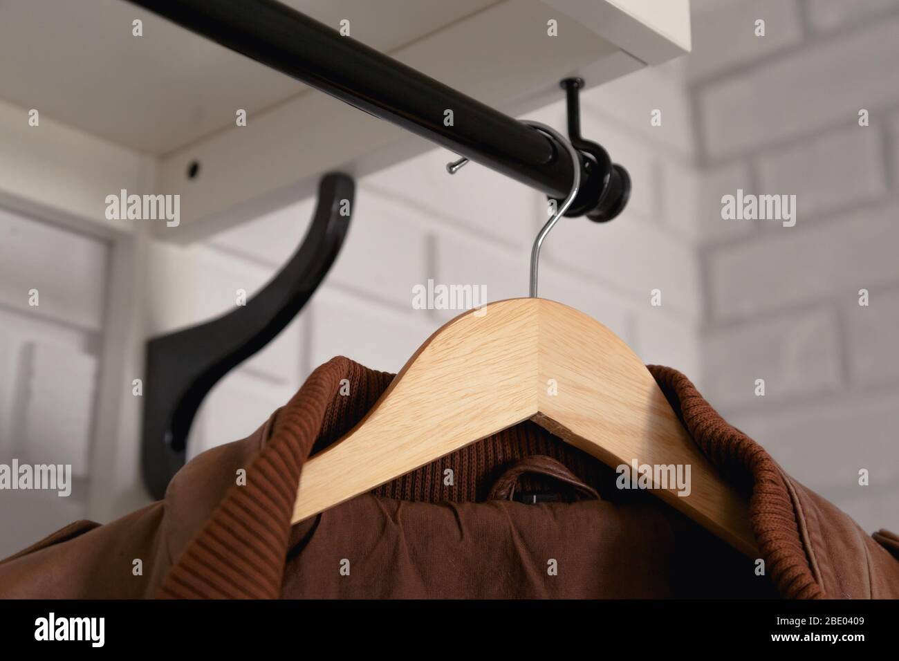 Brown leather jacket hanged on white wall hanger Stock Photo - Alamy