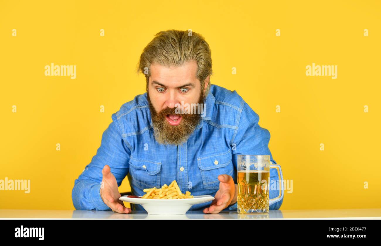 man with fast food. beer and french fries in restaurant. eating and drinking at bar. hipster relax in tavern. bearded guy having snack. lazy man enjoying fresh beer and junk food. Stock Photo