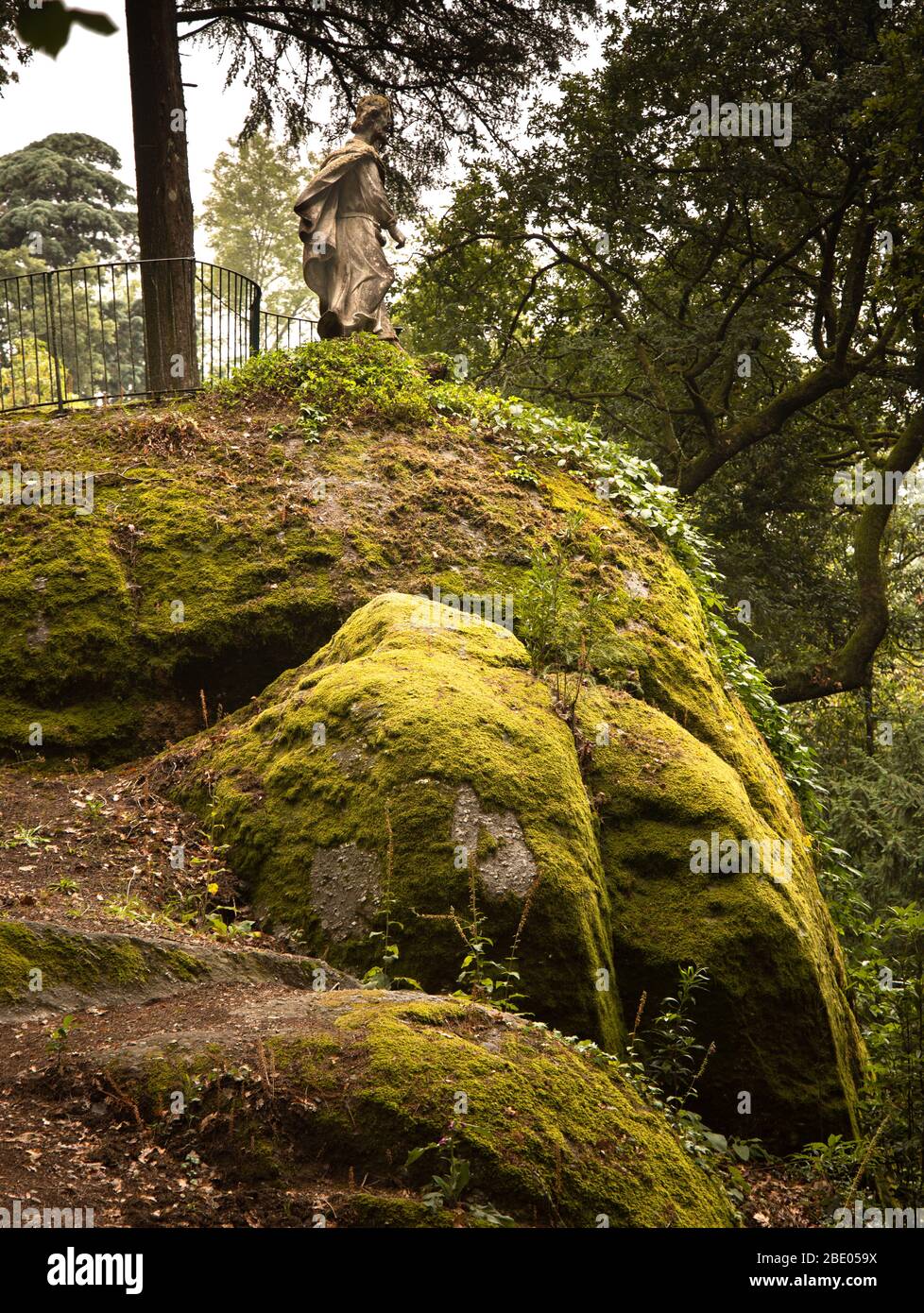 Statue on top of a moss covered huge granite massive rock in the gardens at Santuário do Bom Jesus do Monte Tenões, just outside Braga Portugal Stock Photo