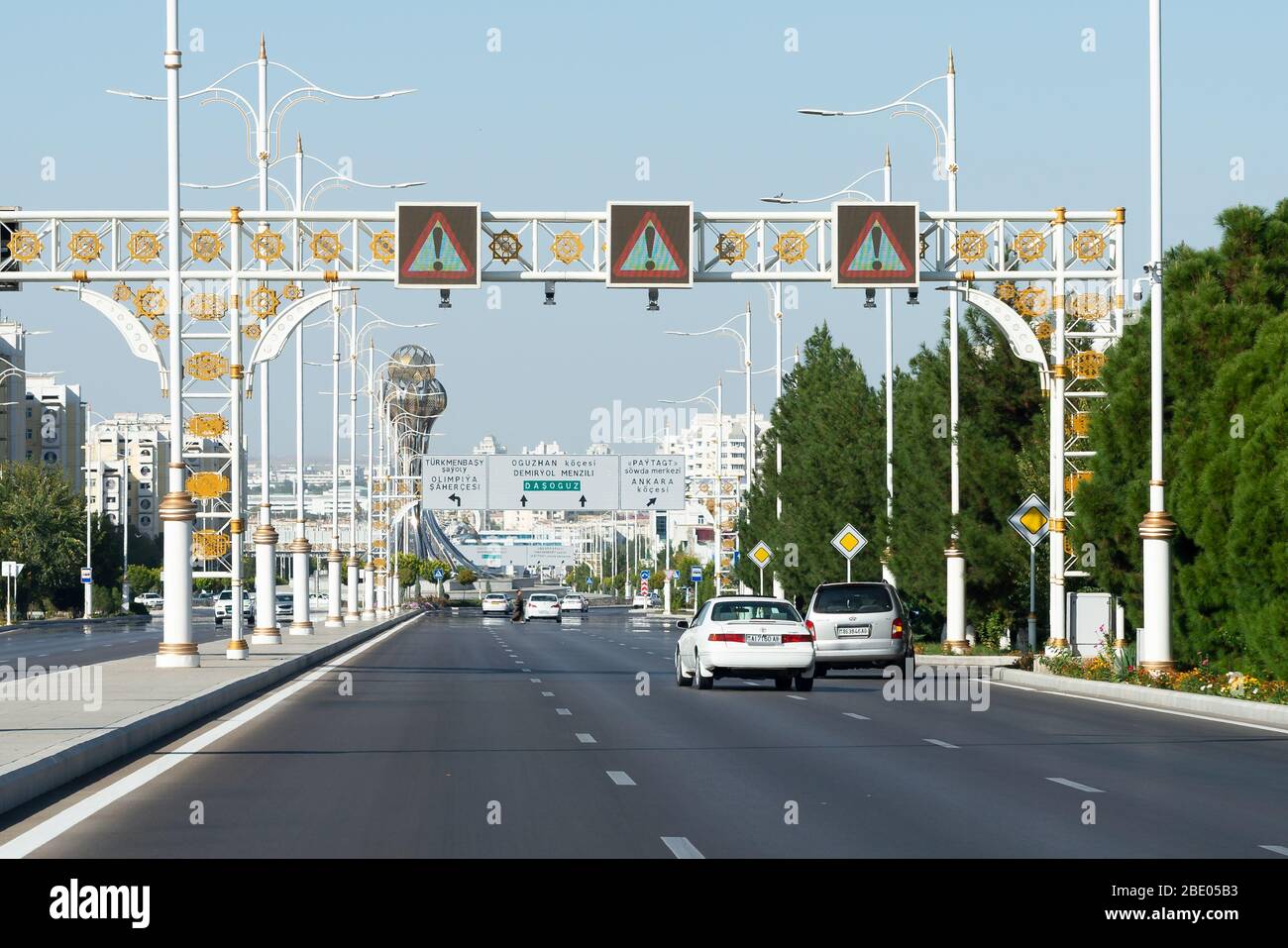 Avenue with overhead road signs decorated with gold. Street traffic or white carst. Ornamented lamp posts. Decorative gold Oguzkhan star. Stock Photo