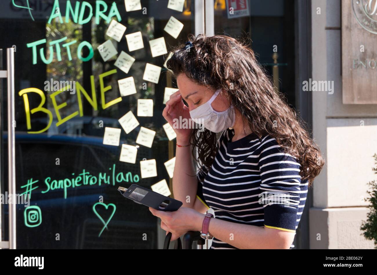 Young woman with mask and waiting in queue to enter supermarket in Milan, Italy during coronavirus crisis. Andrà tutto bene - Everything will be fine Stock Photo