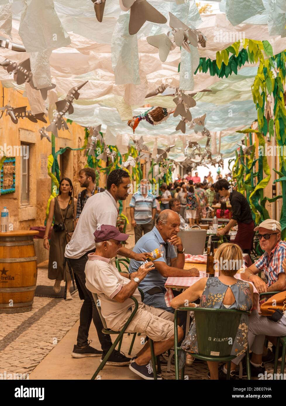 Outside dining in a colourful decorated street during traditional Festa dos Tabuleiros Festival of the Trays Tomar Portugal. Stock Photo