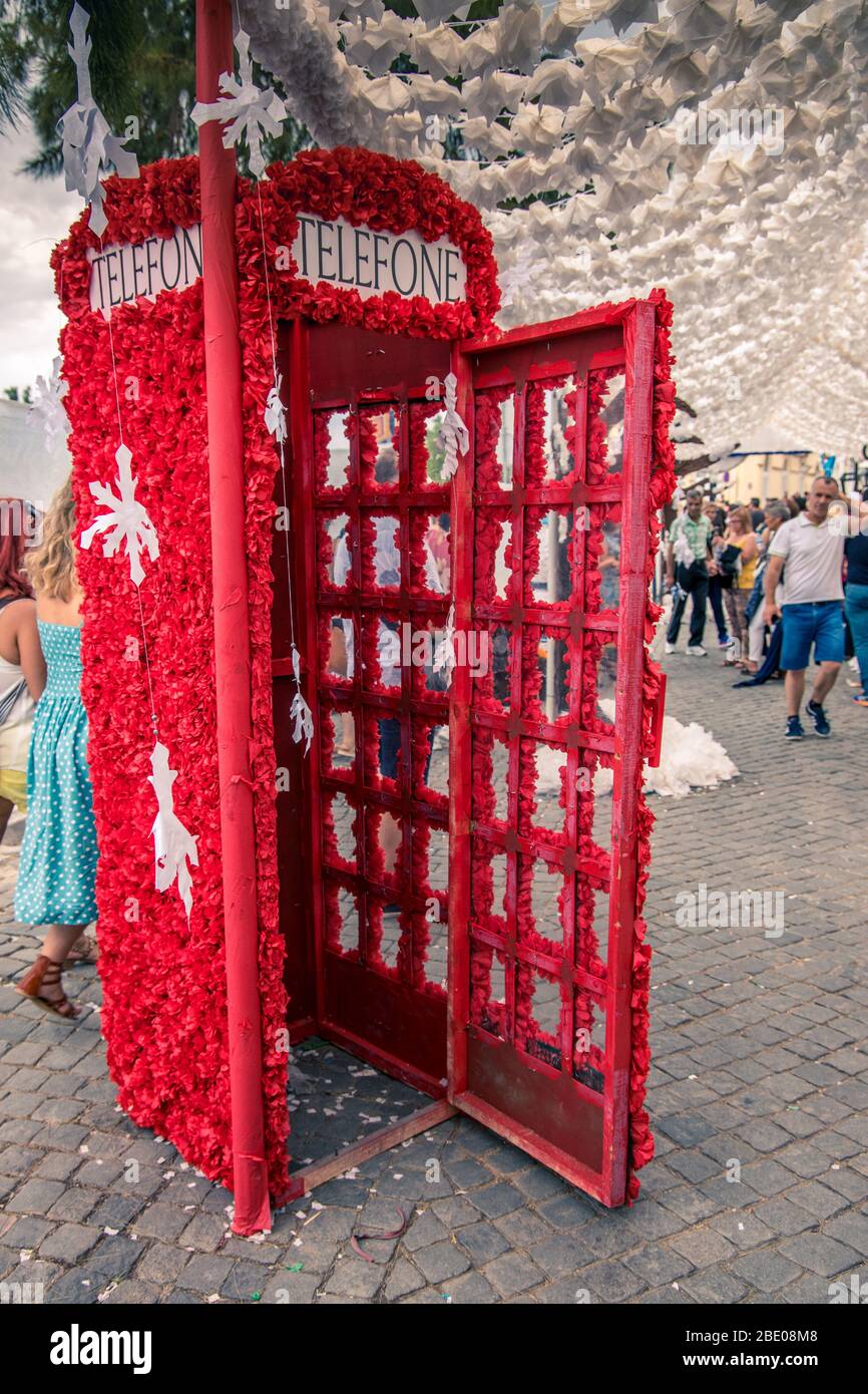 A red telephone box decorated with red flower during the Tomar traditional Festa dos Tabuleiros (Festival of the Trays). Portugal Stock Photo