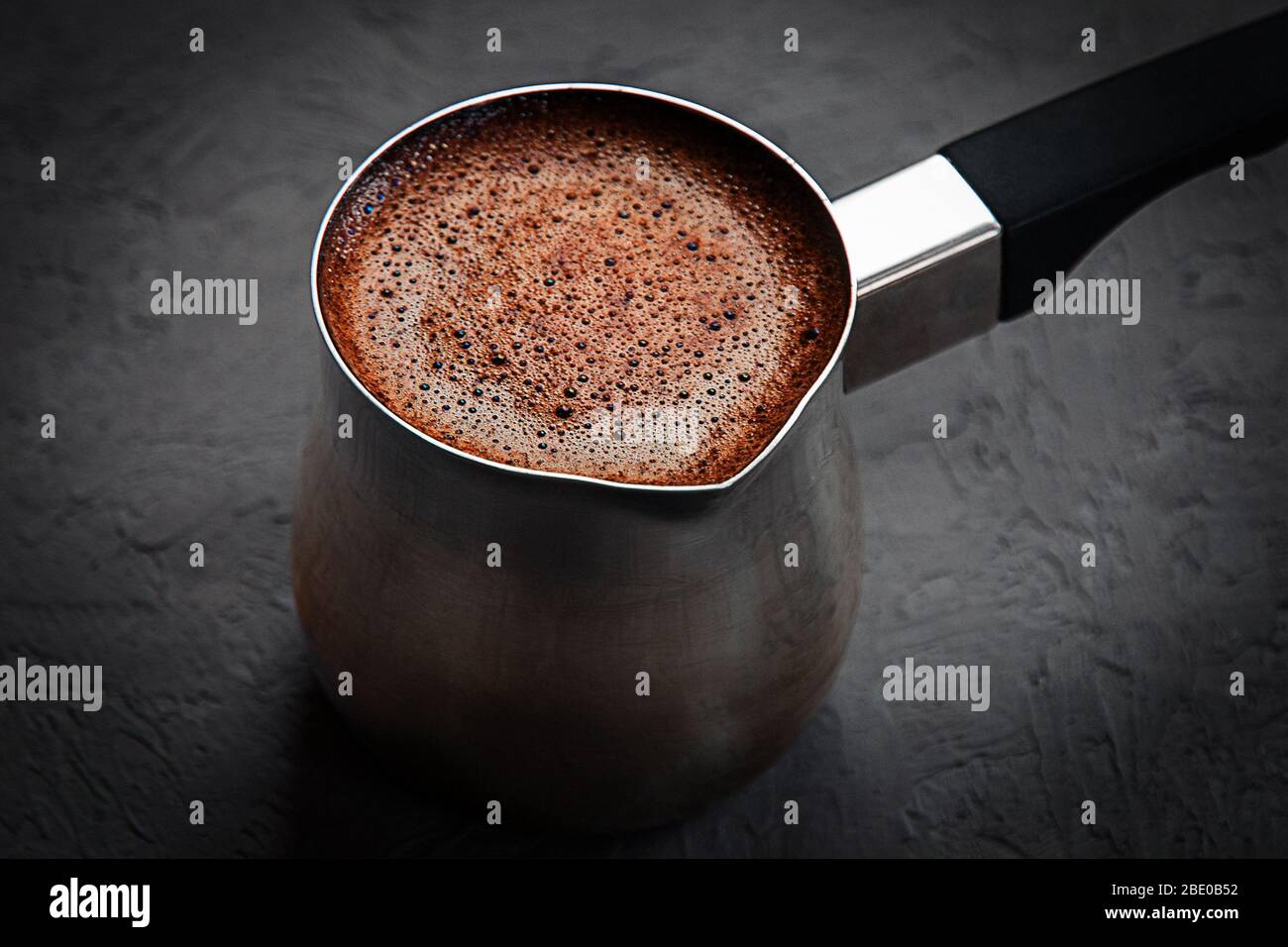 coffee with brown froth brewed in cezve on dark gray background Stock Photo