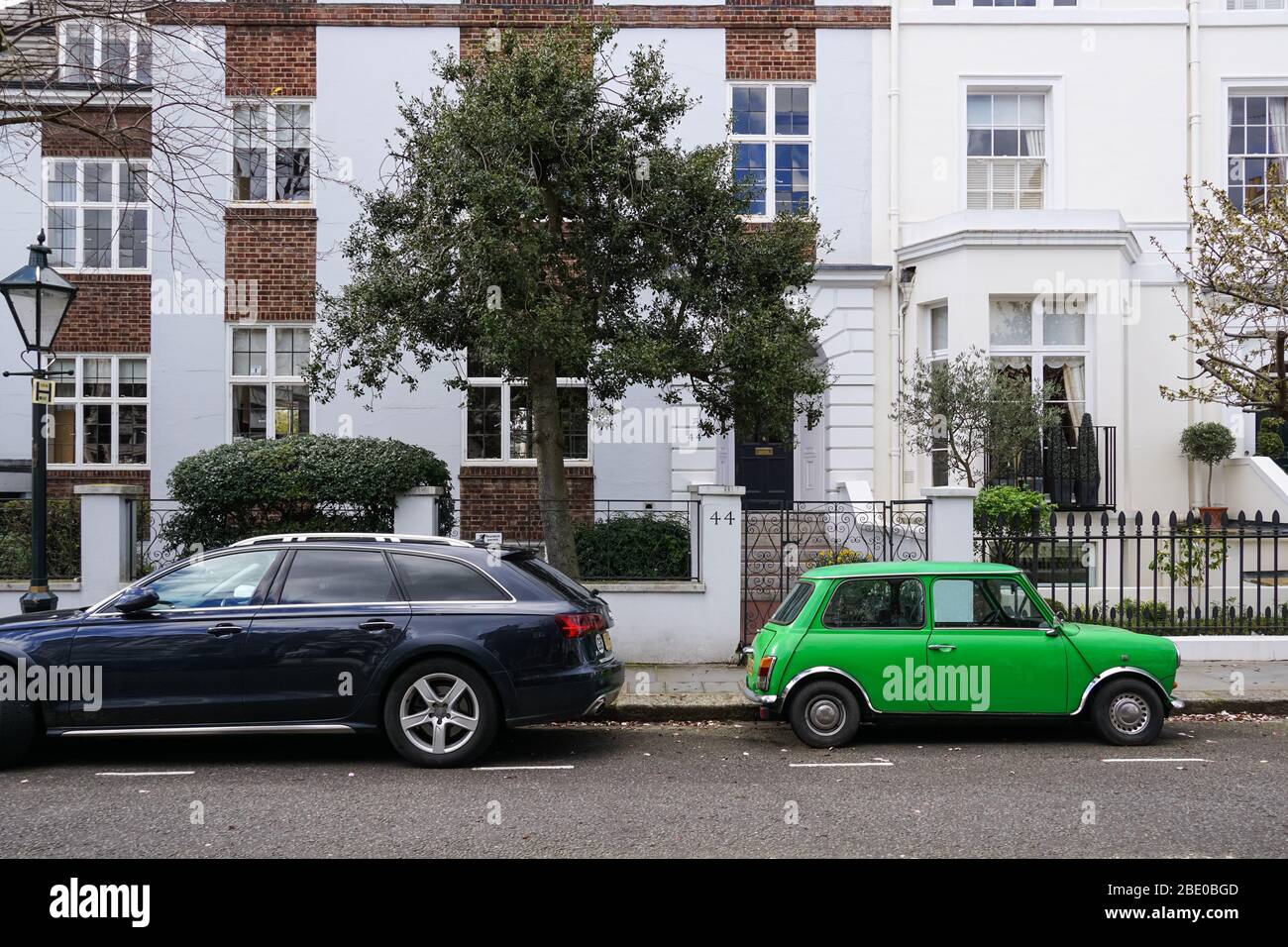 Old vintage two-door Morris Mini Cooper car parked next to modern Audi A4 Avant car in front of residential buildings London England United Kingdom UK Stock Photo