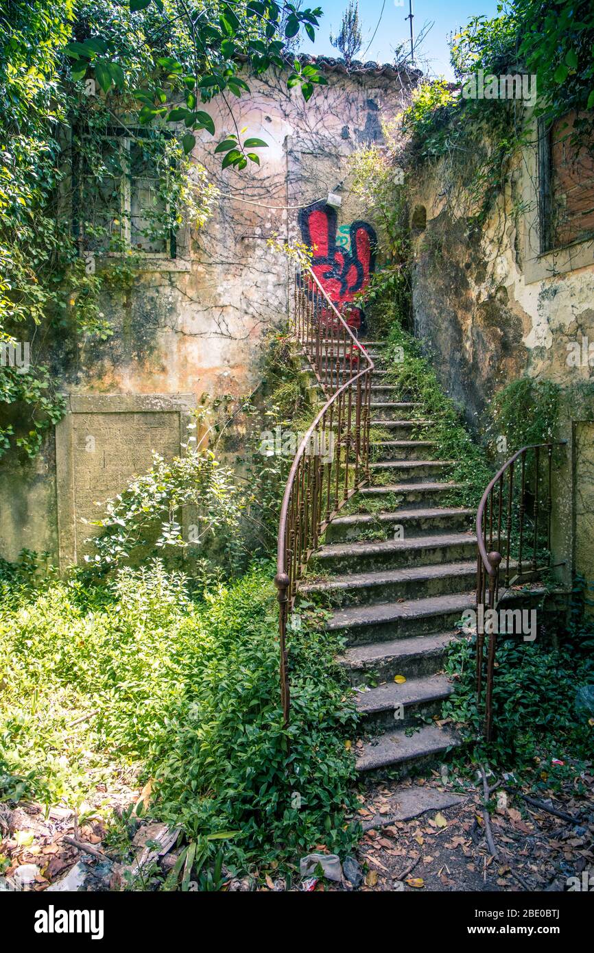 Old iron twisting overgrown staircase with Graffiti painted on old door at top in Sintra near Lisbon Portugal Stock Photo
