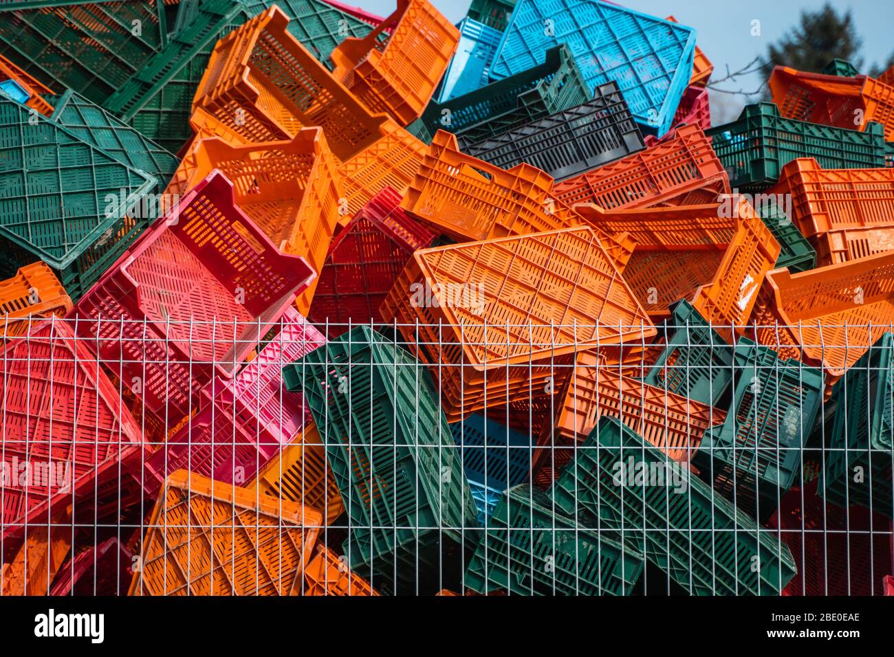 Old plastic boxes in a warehouse as a trash behind the metal mesh fence