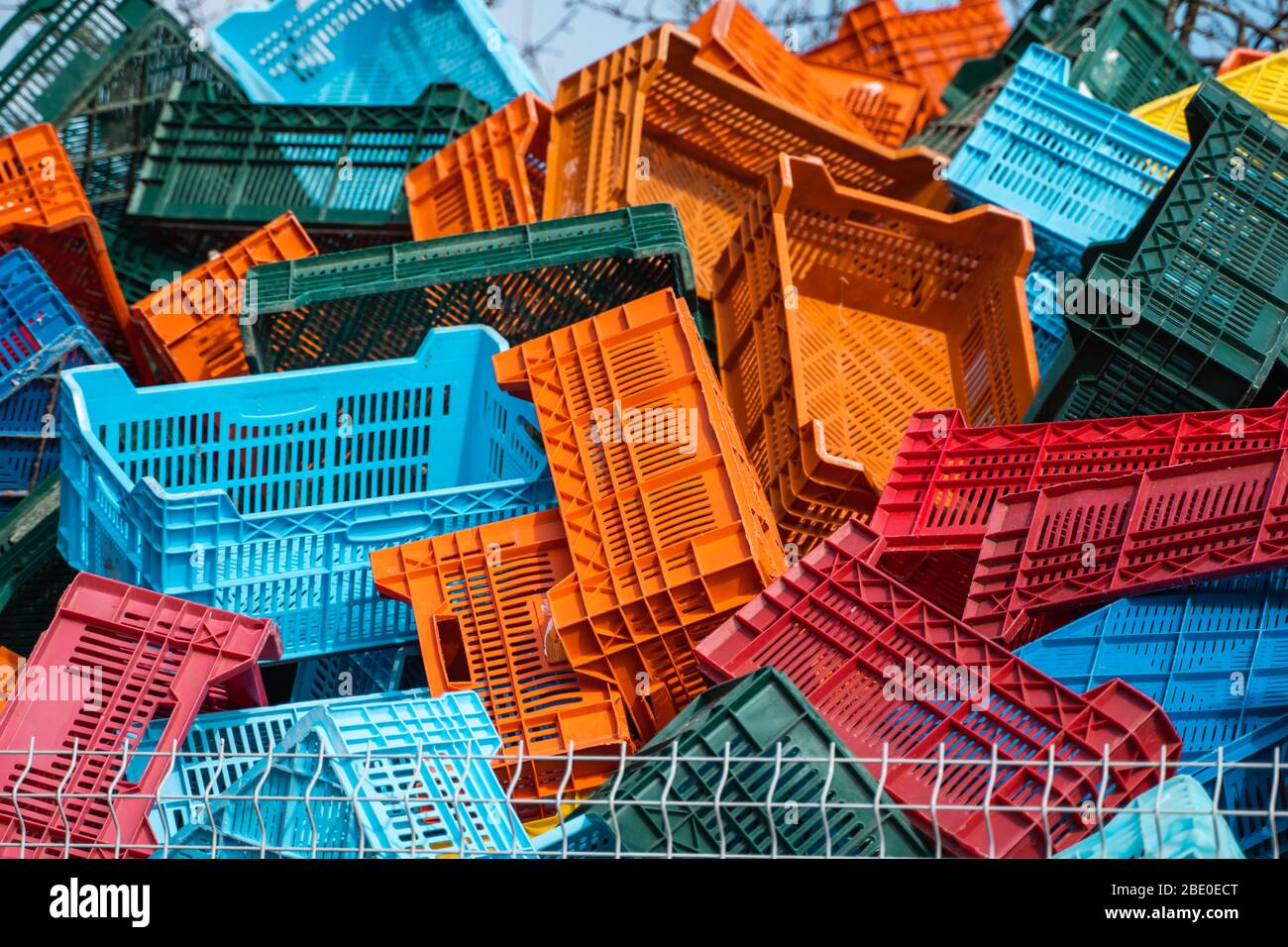 Old plastic boxes in a warehouse as a trash behind the metal mesh fence