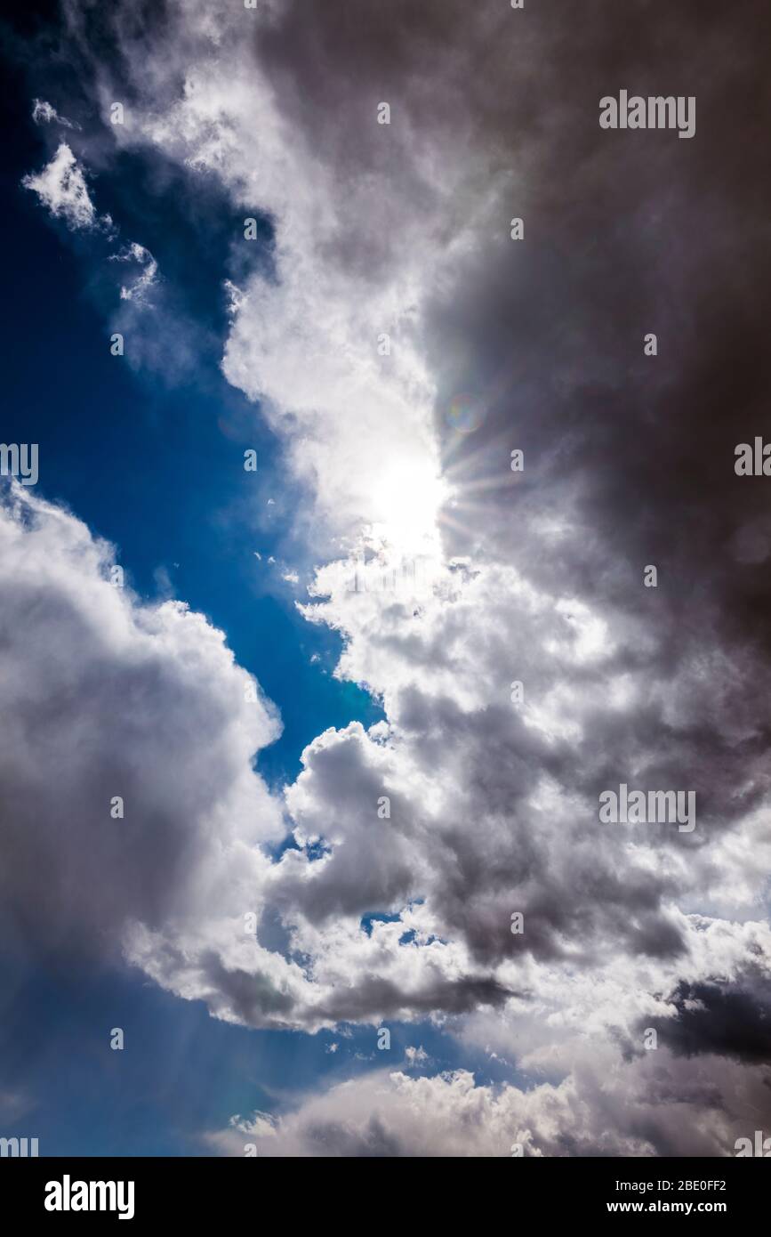 Unusual cloud formations & sunburst against clear cobalt blue sky; central Colorado; USA Stock Photo