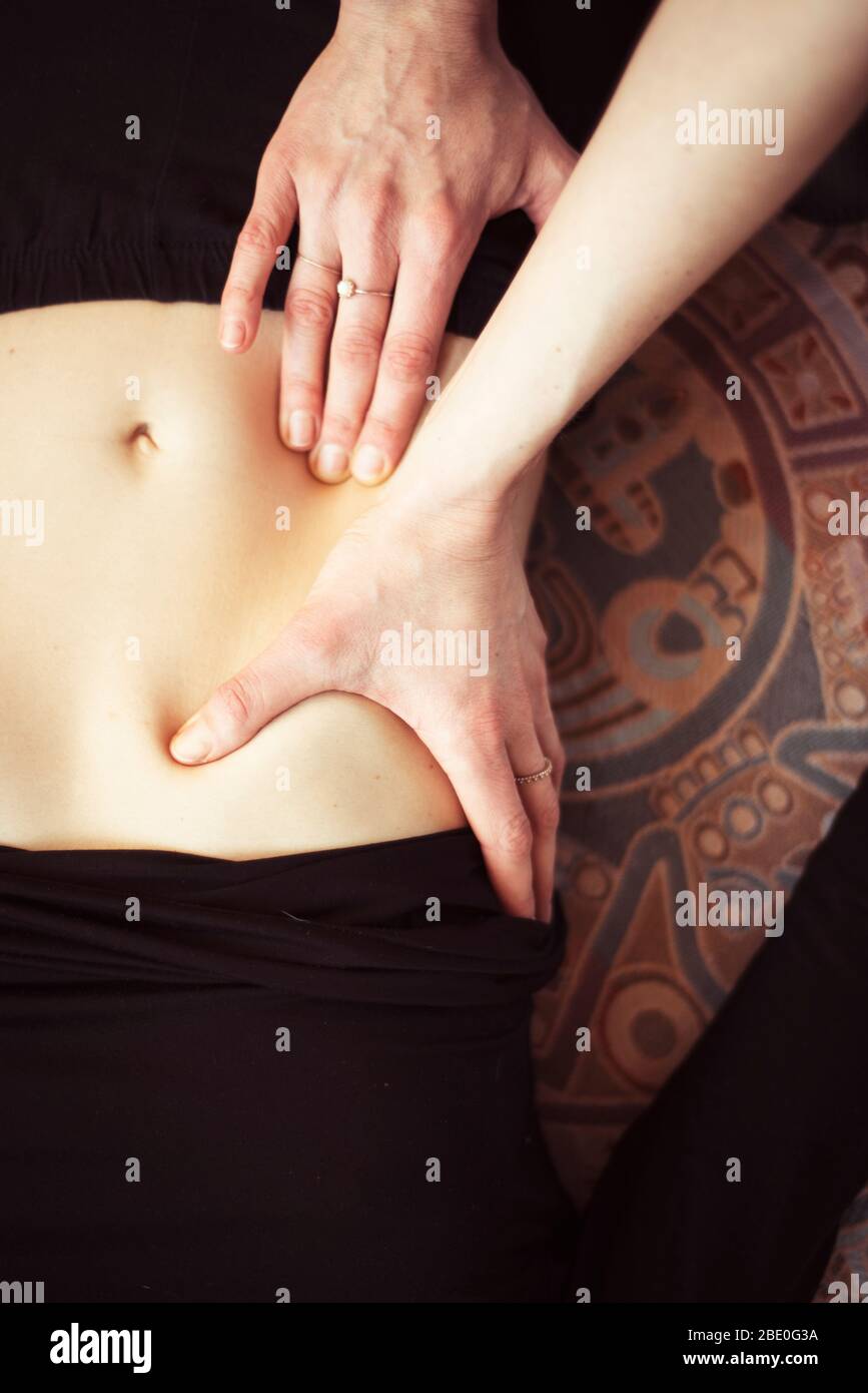 close up detail of hands massaging stomach in work from home set up Stock Photo