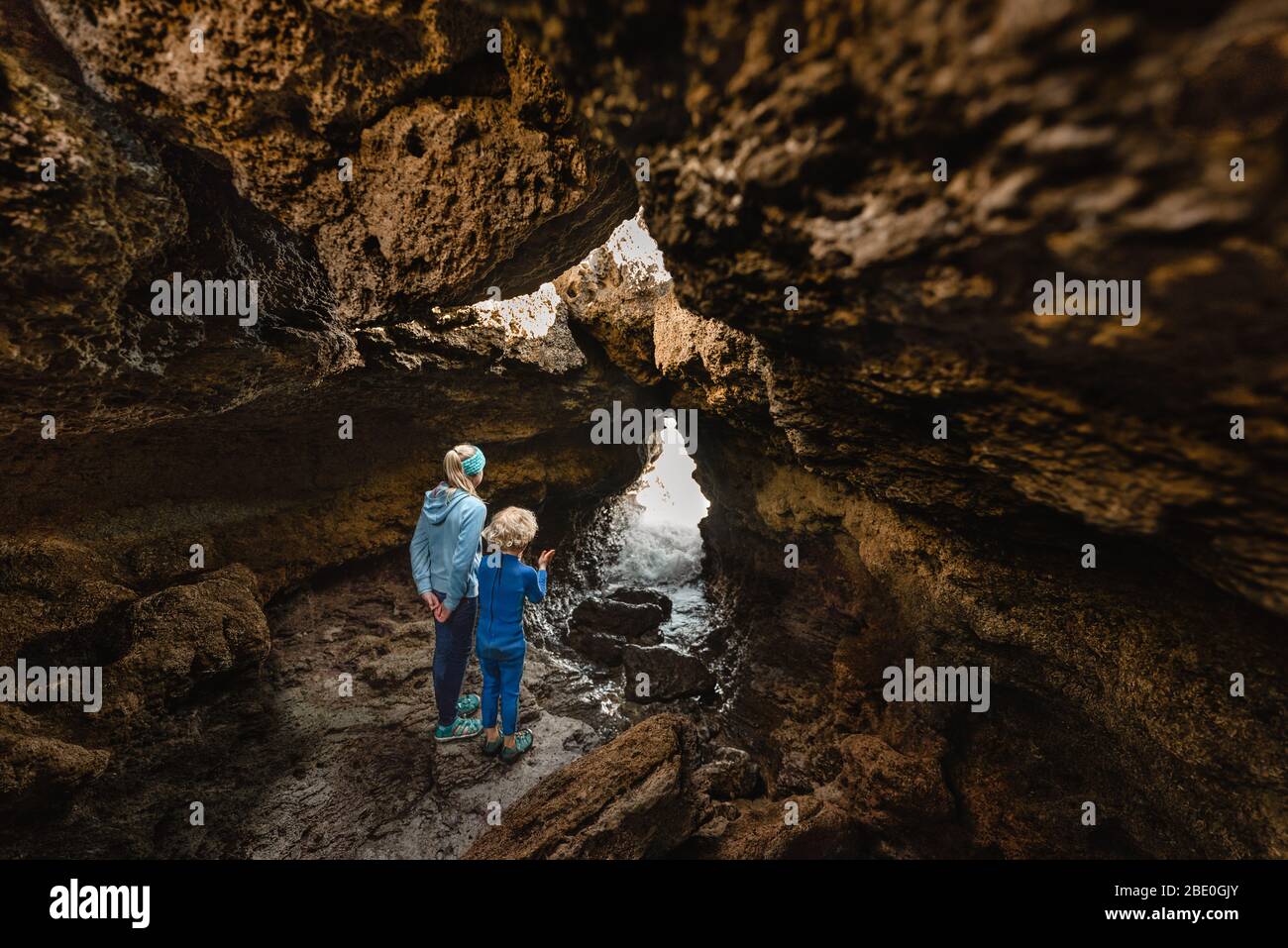 Siblings exploring sea cave in New Zealand Stock Photo