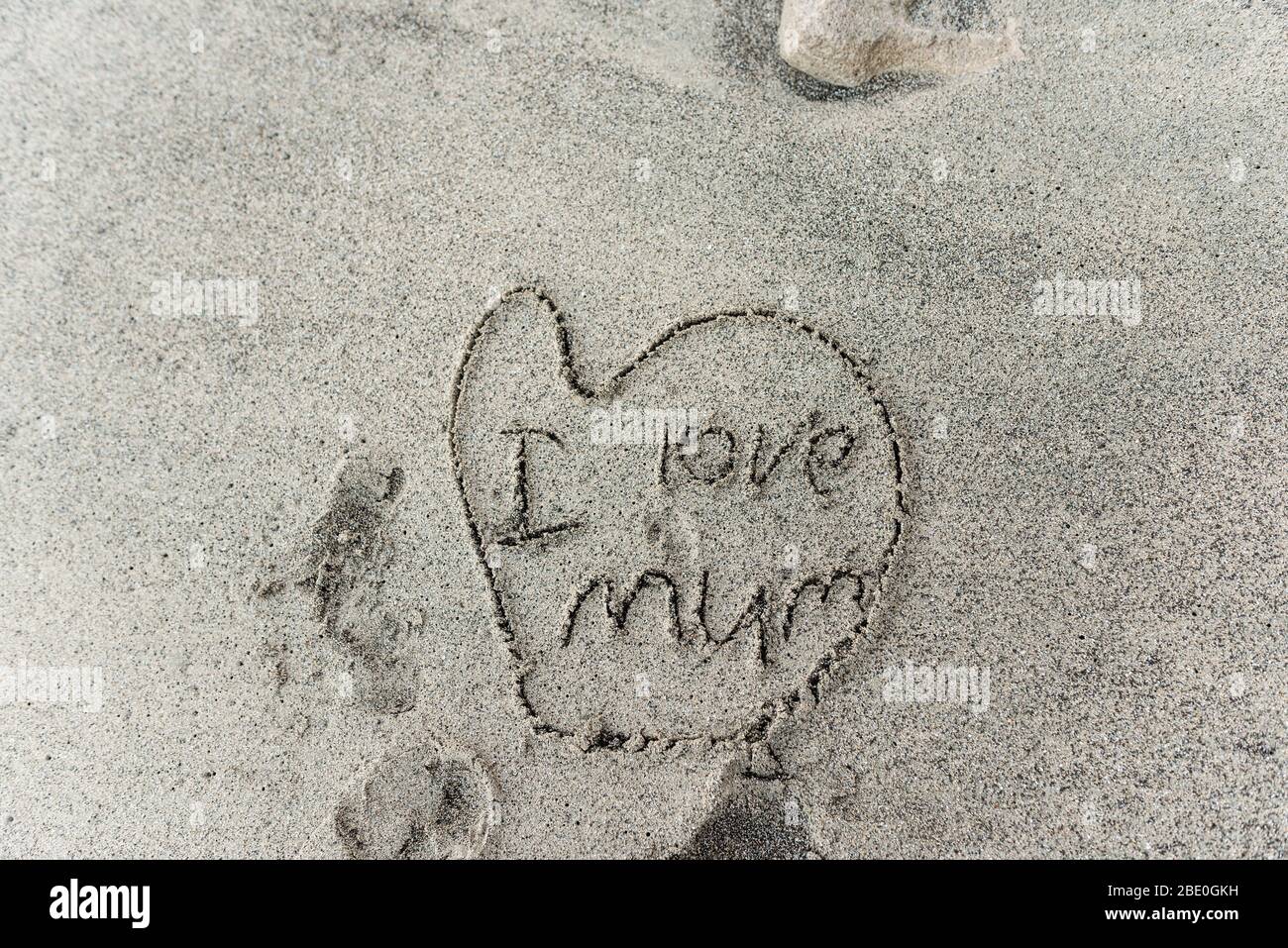 Child's drawing in sand of heart with I love mum written inside Stock Photo