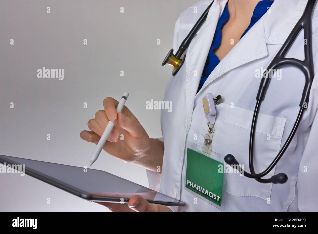 Pharmacist working on tablet. Stethoscope over shoulder, badge visible Stock Photo