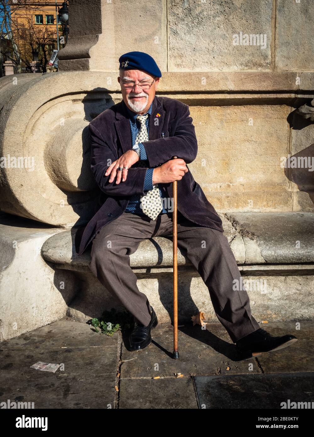 Older man wearing a Spanish Legion cap badge relaxing in the sunshine on the Promenade Passeig de Lluís Companys, Barcelona, Spain. Stock Photo