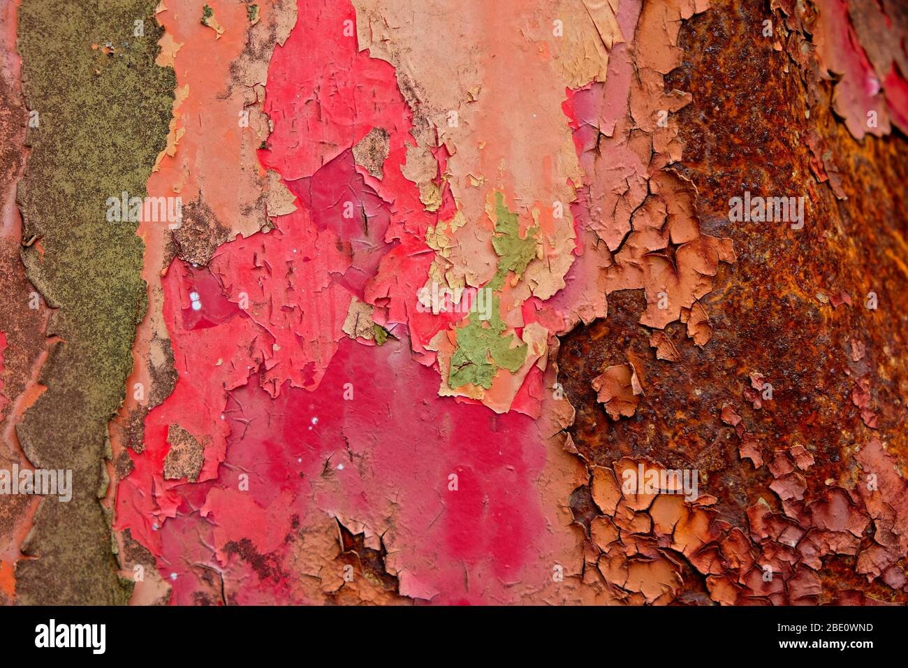 Multiple layers of flaking paint on a metal surface with severe rusting. Stock Photo