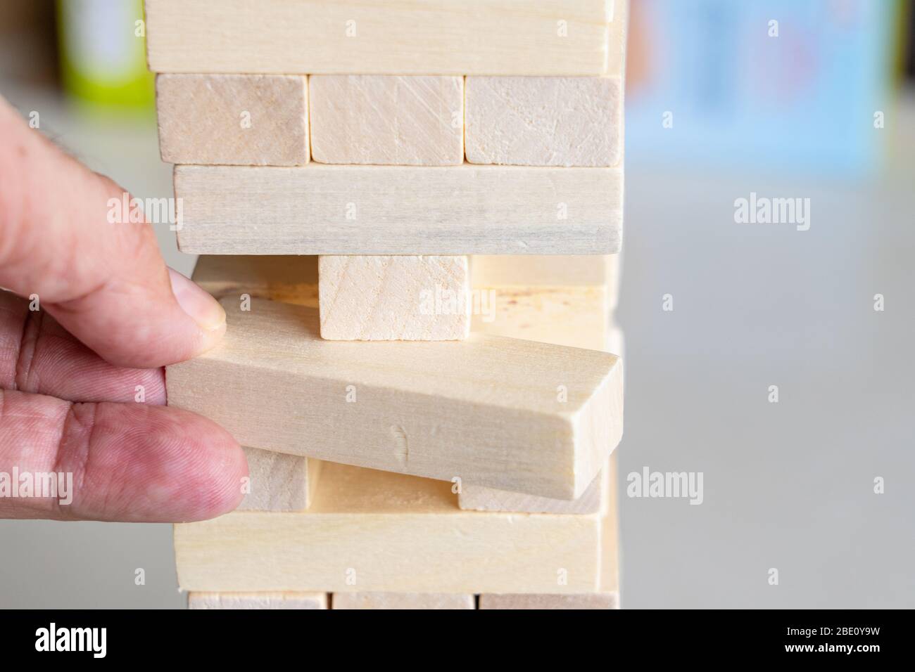 A man carefully removes a wooden block form a Jenga tower Stock Photo