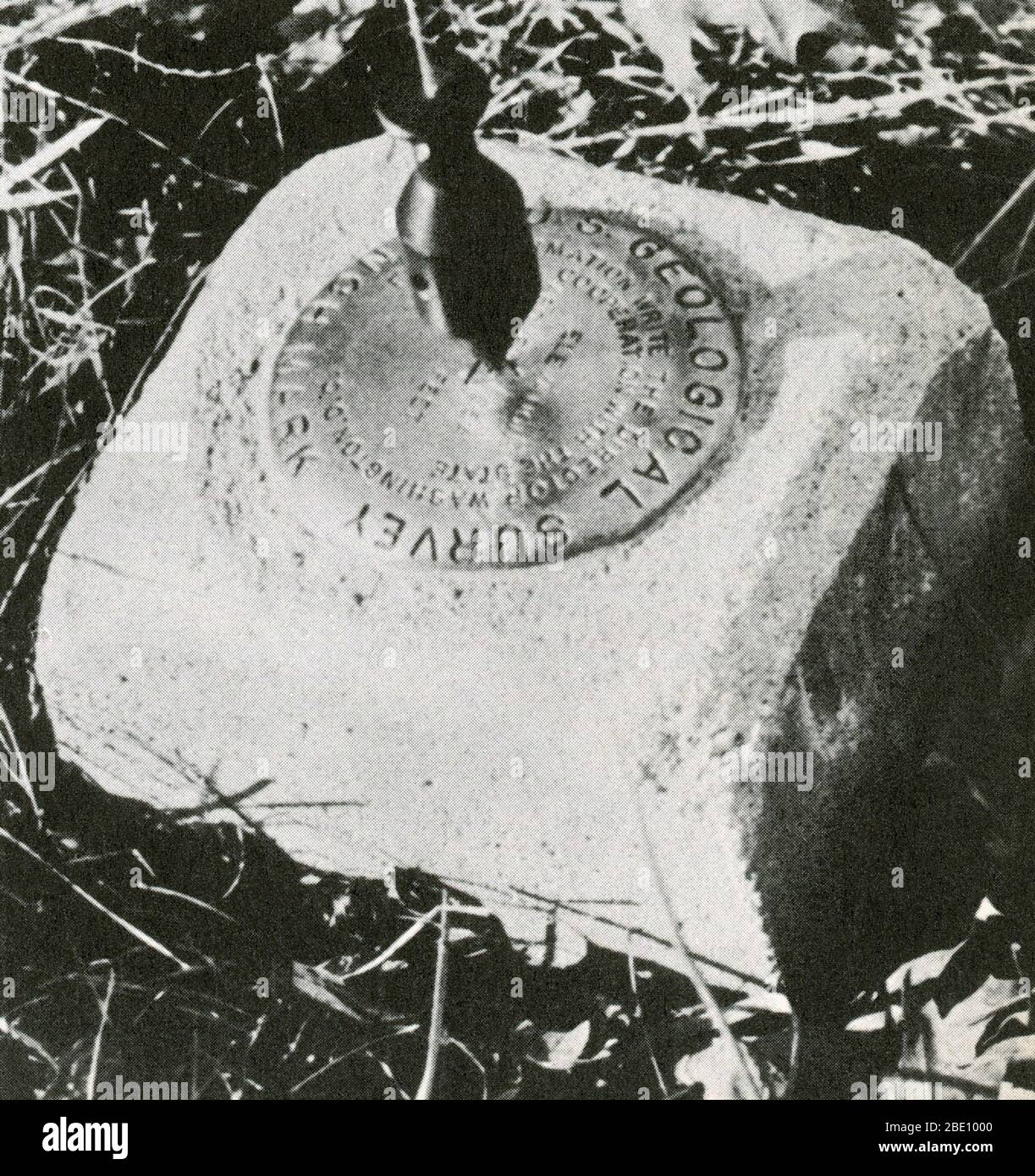 Close up of a benchmark, with a surveyor's plumb-bob visible, hanging above. The benchmark acts as a point of reference for any future measurements. Stock Photo