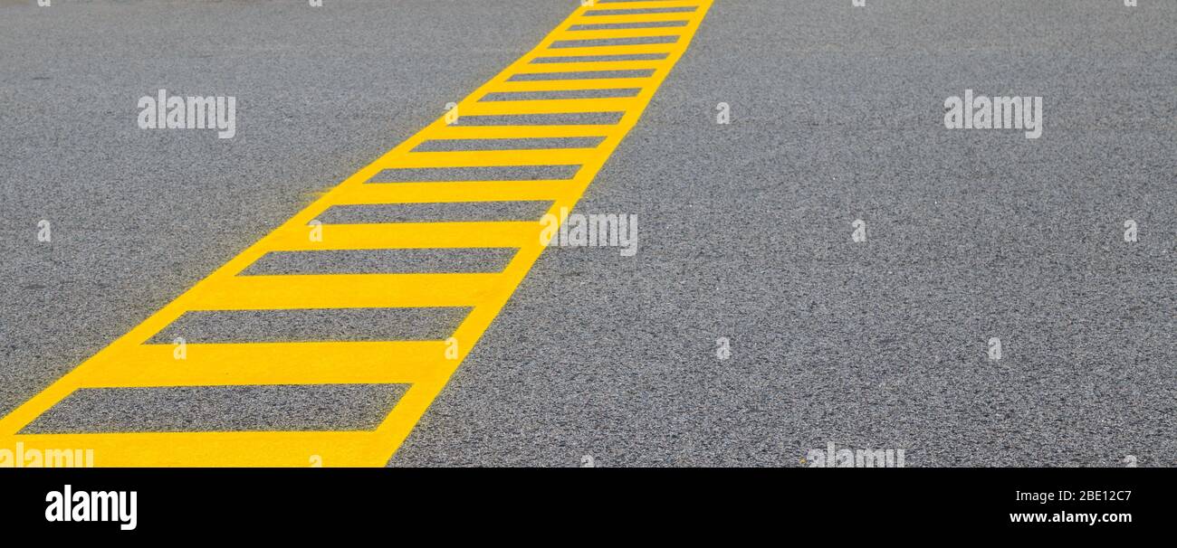 Yellow painted crossing on grey road. Header with copy space. Minimalist image Stock Photo