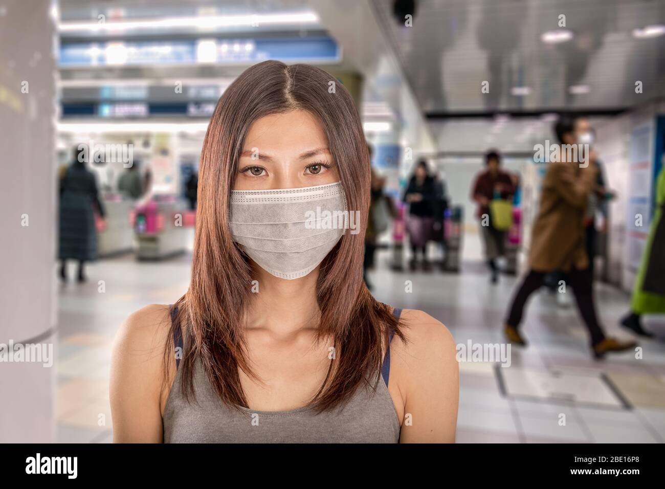 Chinese woman wearing surgical mask with defocused Japanese metro train station in background