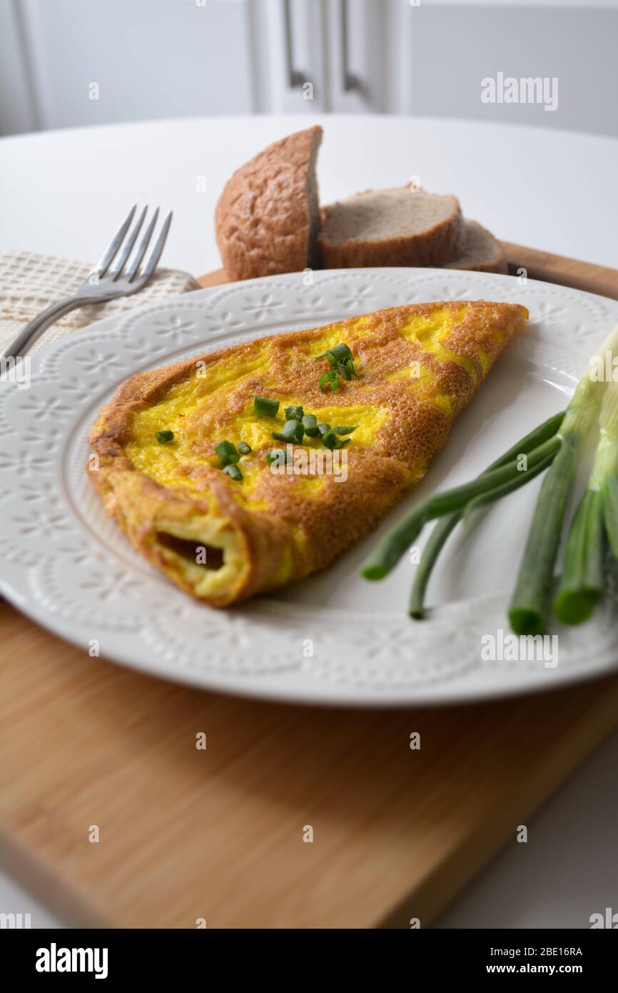 https://c8.alamy.com/comp/2BE16RA/fluffy-breakfast-omelette-with-green-spring-onions-and-fresh-toast-bread-on-a-wooden-surface-with-a-napkin-and-metal-fork-2BE16RA.jpg