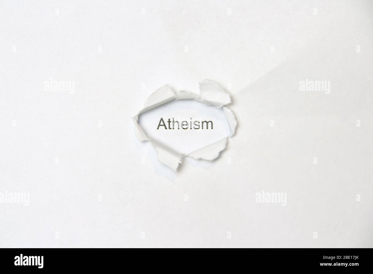 Word atheism on white isolated background, the inscription through the wound hole in the paper. Stock photo for web and print with empty space for text and design. Stock Photo