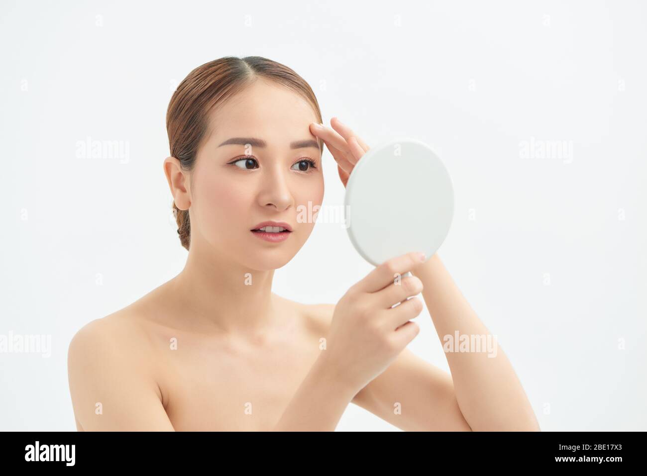 Beautiful Asian woman checking her skin, skin care, acne treatment. Spa and skincare concept. Stock Photo