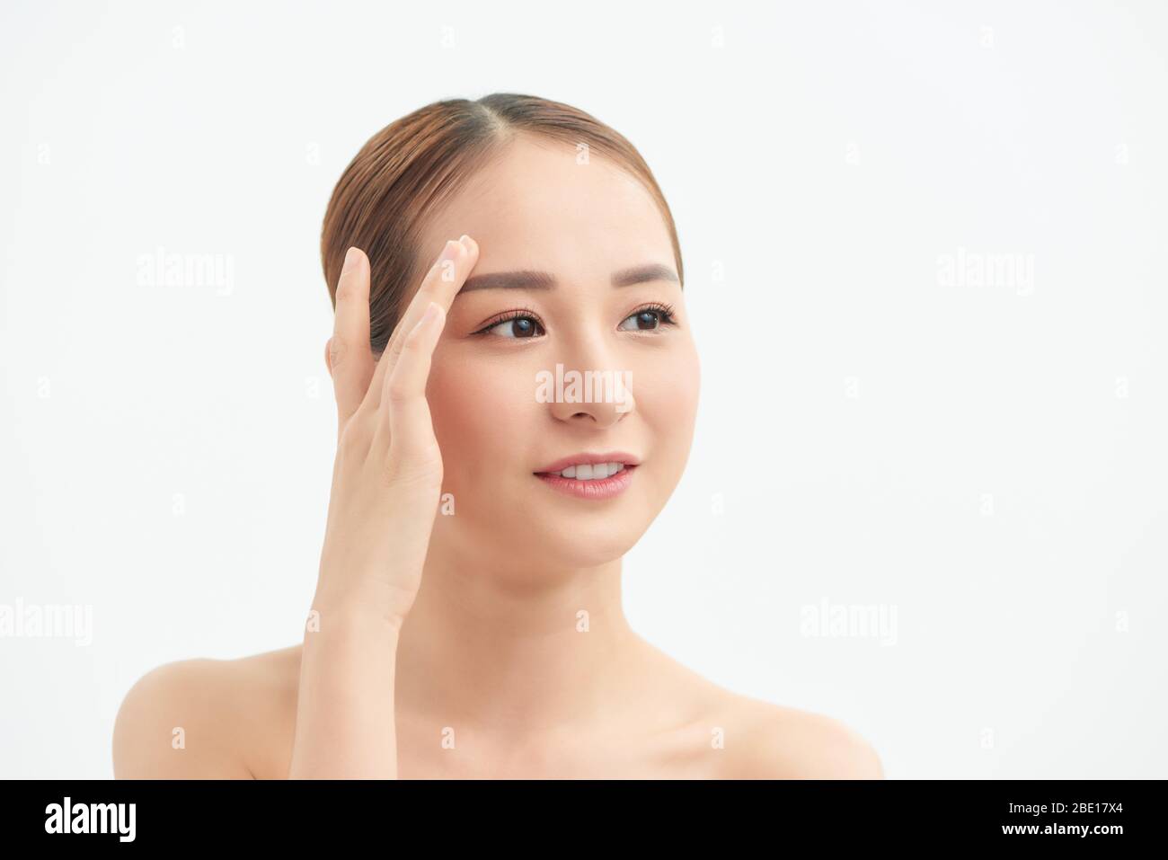 Attractive young Asian girl touching her face on white background ...