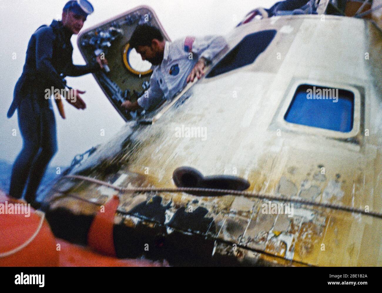 Astronaut Walter M. Schirra, Jr., Apollo 7 commander, egresses the spacecraft during recovery operations in the Atlantic. He is assisted by a member of the U.S. Navy frogman team. The Apollo 7 spacecraft splashed down at 7:11 a.m., October 22, 1968, approximately 200 nautical miles south-southwest of Bermuda. Stock Photo