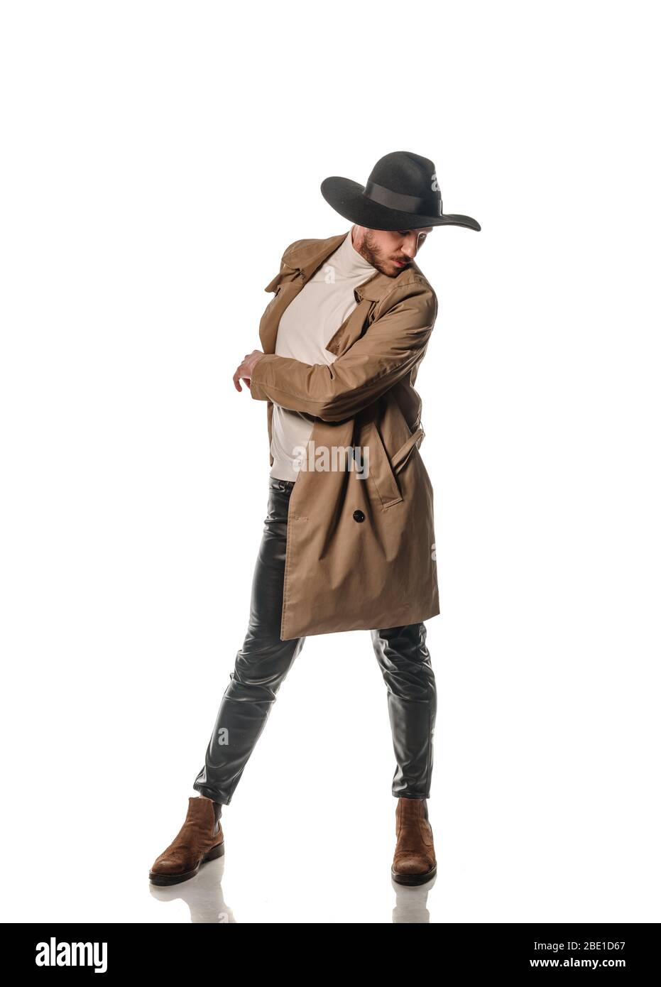 Attractive young male model posing in leather pants and long coat isolated on white backgorund Stock Photo