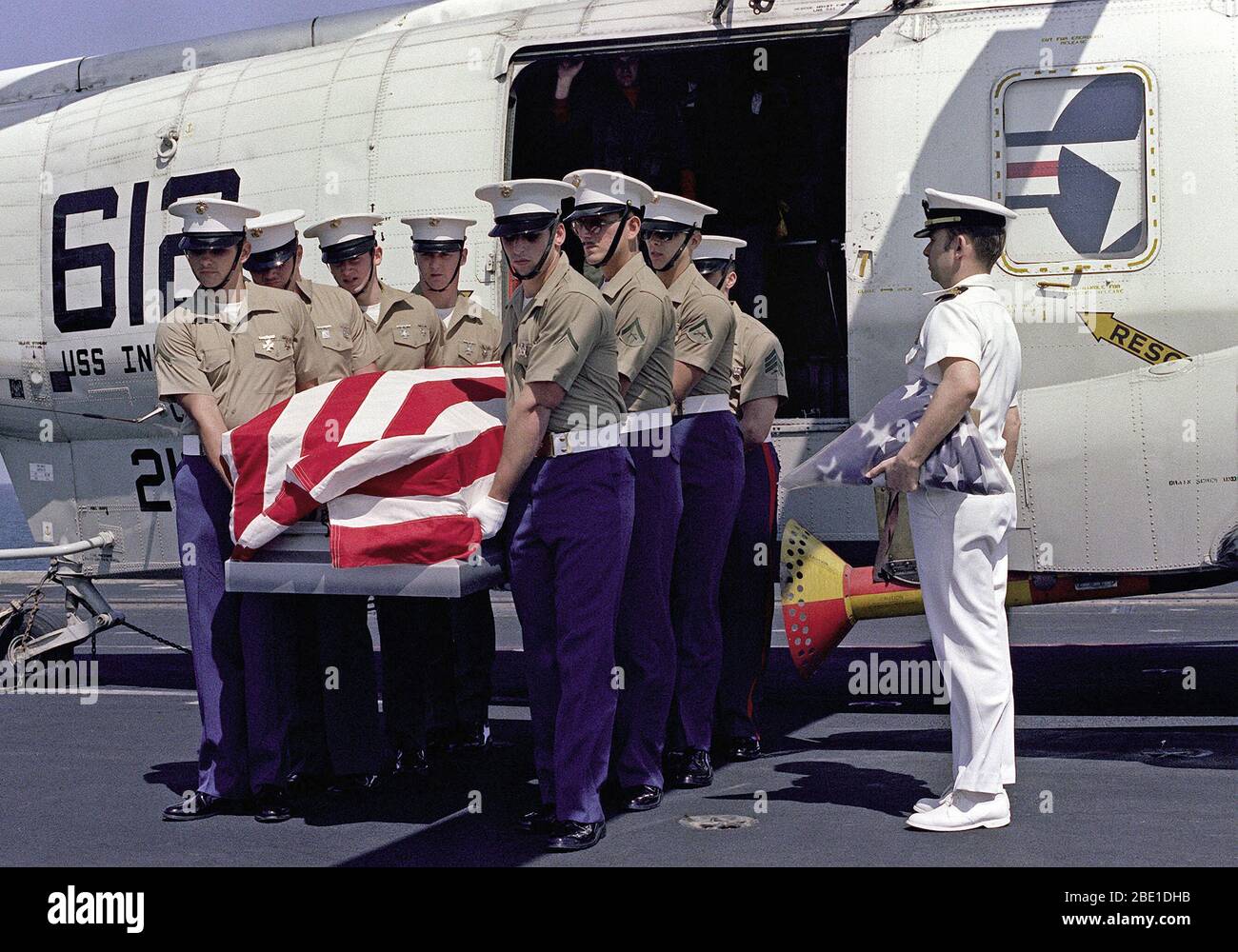 1982 - U.S. Marines aboard the aircraft carrier USS INDEPENDENCE (CV-62) offload the remains of a commander from an SH-3 Sea King helciopter, attached to Carrier Air Wing 6 (CVW-6). Stock Photo