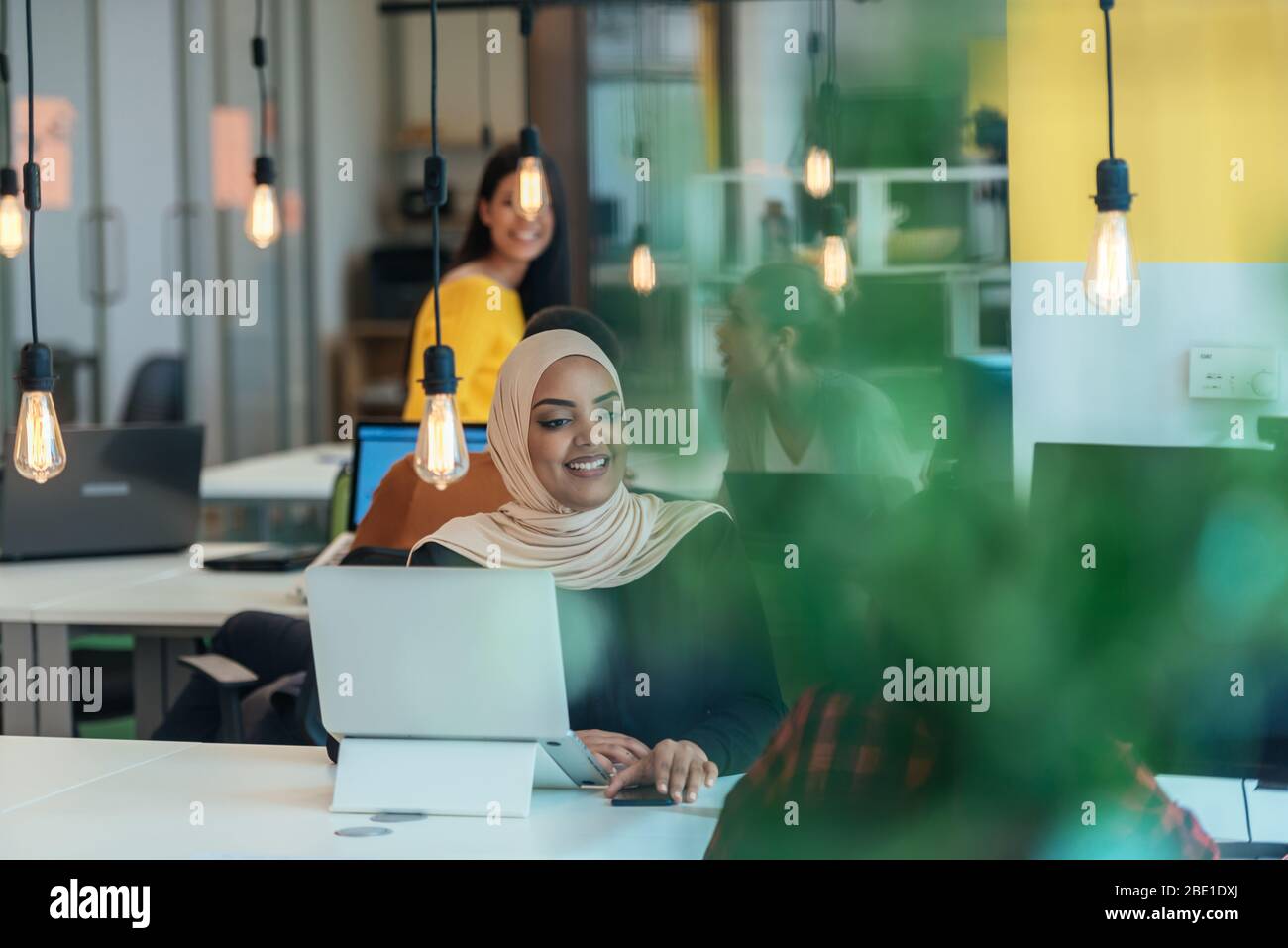 African muslim girl wearing hijab working on a laptop in a modern ...