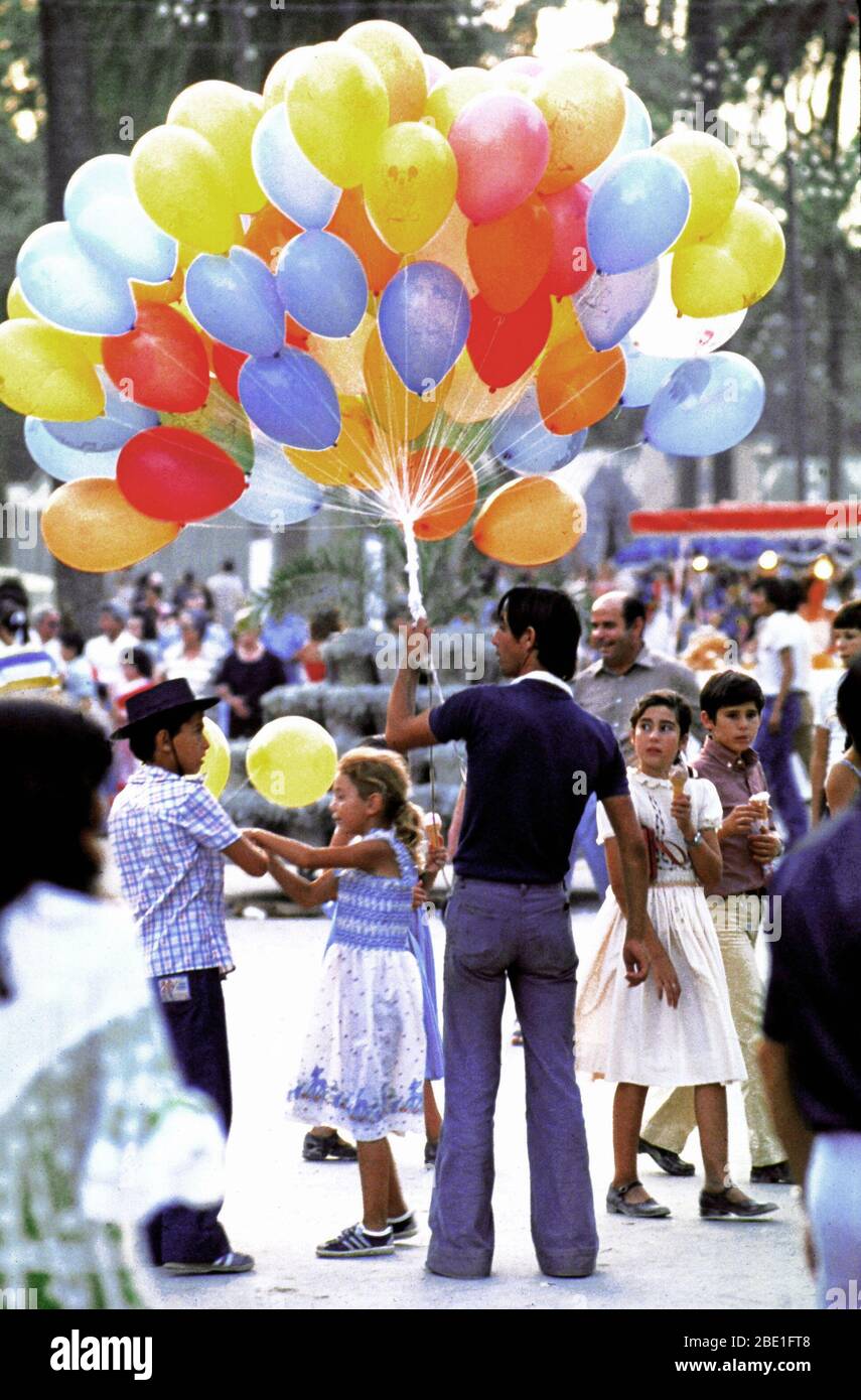 1981 - A balloon vender holds his colorful merchandise while awaiting customers at a local fair. Stock Photo