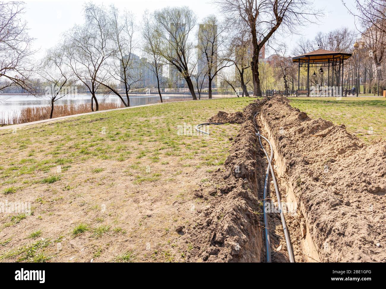 Installation of tubes for an irrigation system in the ground under the trees close to the river. Watering system in the Natalka park of Kiev, Ukraine Stock Photo
