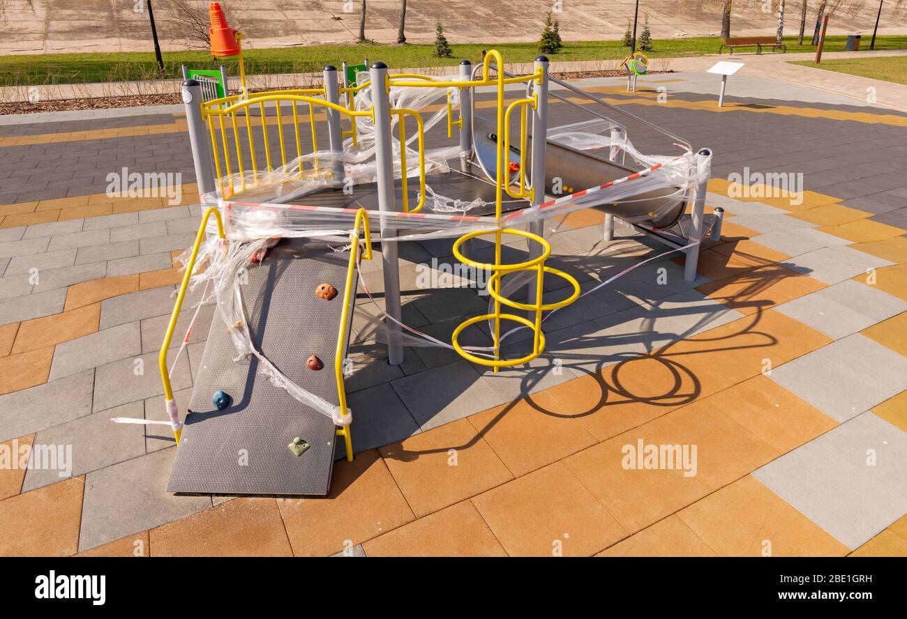 Children's playground, in Kiev, Ukraine, closed due to containment due to a coronavirus outbreak, covid-19. The games are wrapped in cellophane to pre Stock Photo