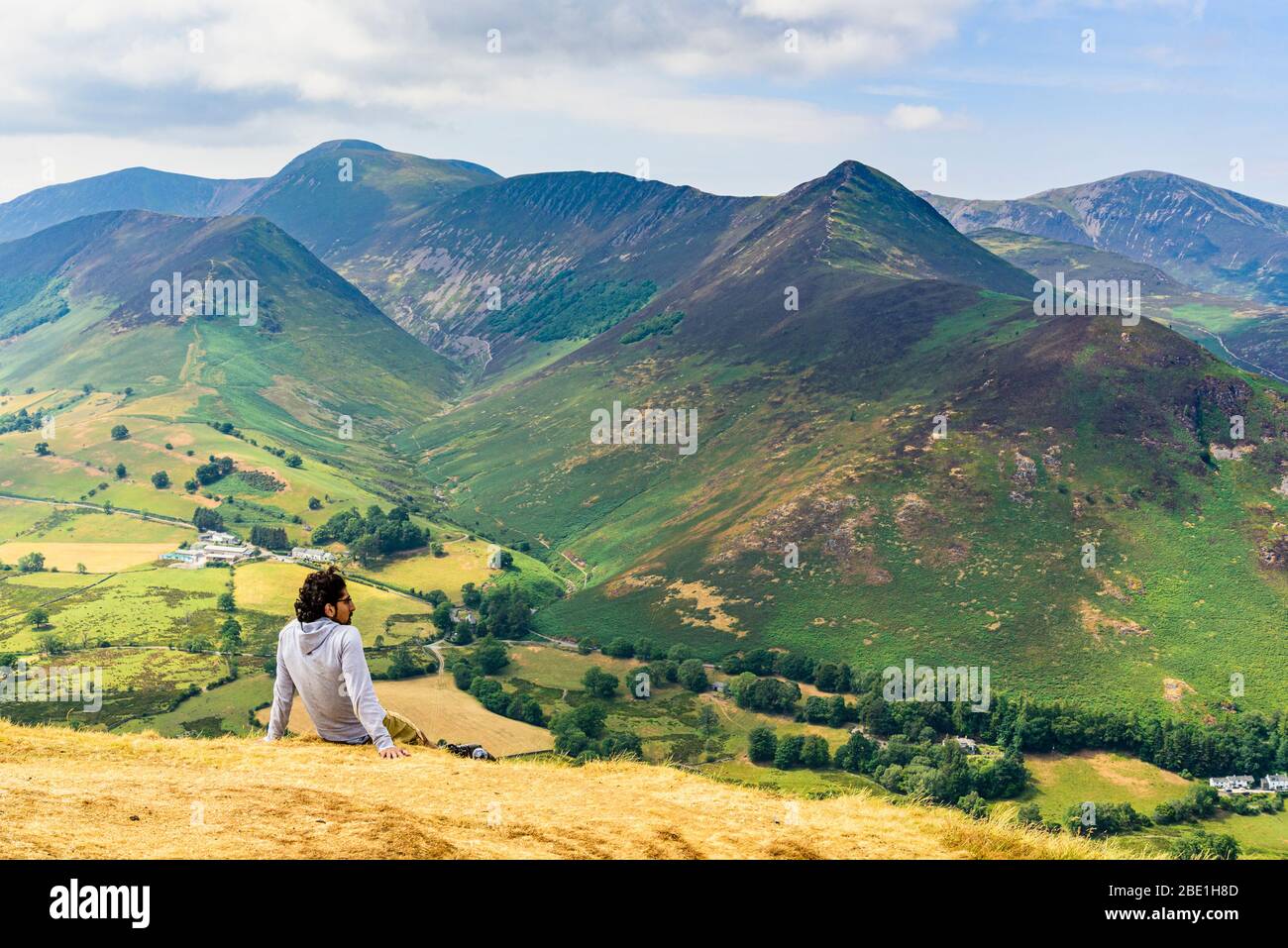 A hiker rests on Catbells in the English Lake District looking over Newlands valley to fells including Grasmoor Causey Pike and Grisedale Pike Stock Photo