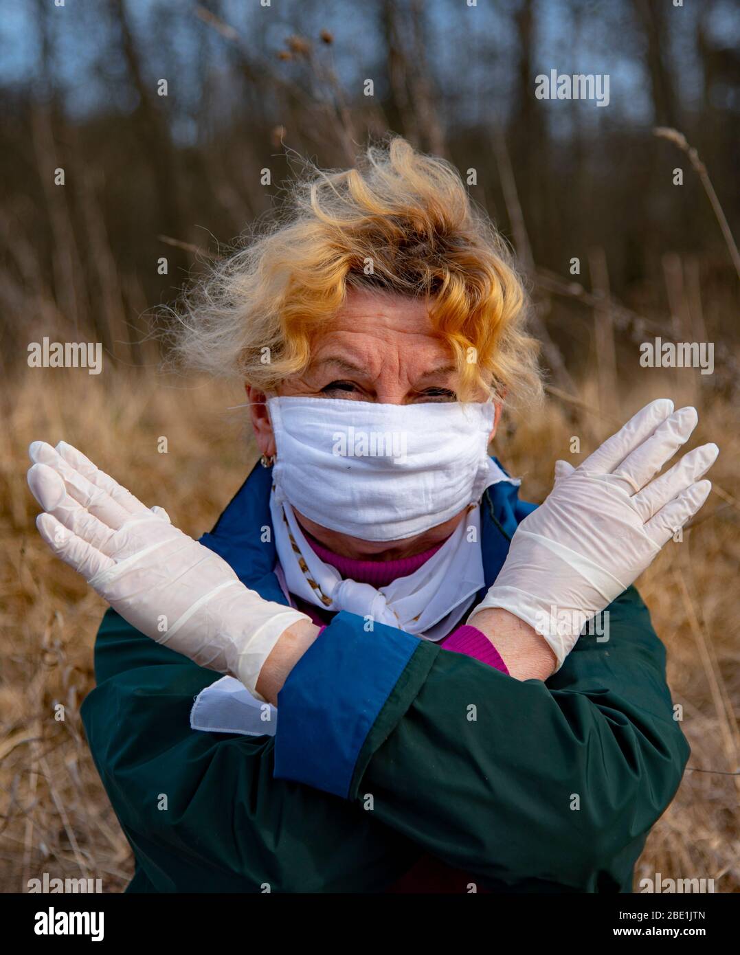An elderly woman in a medical protective mask and rubber gloves ...