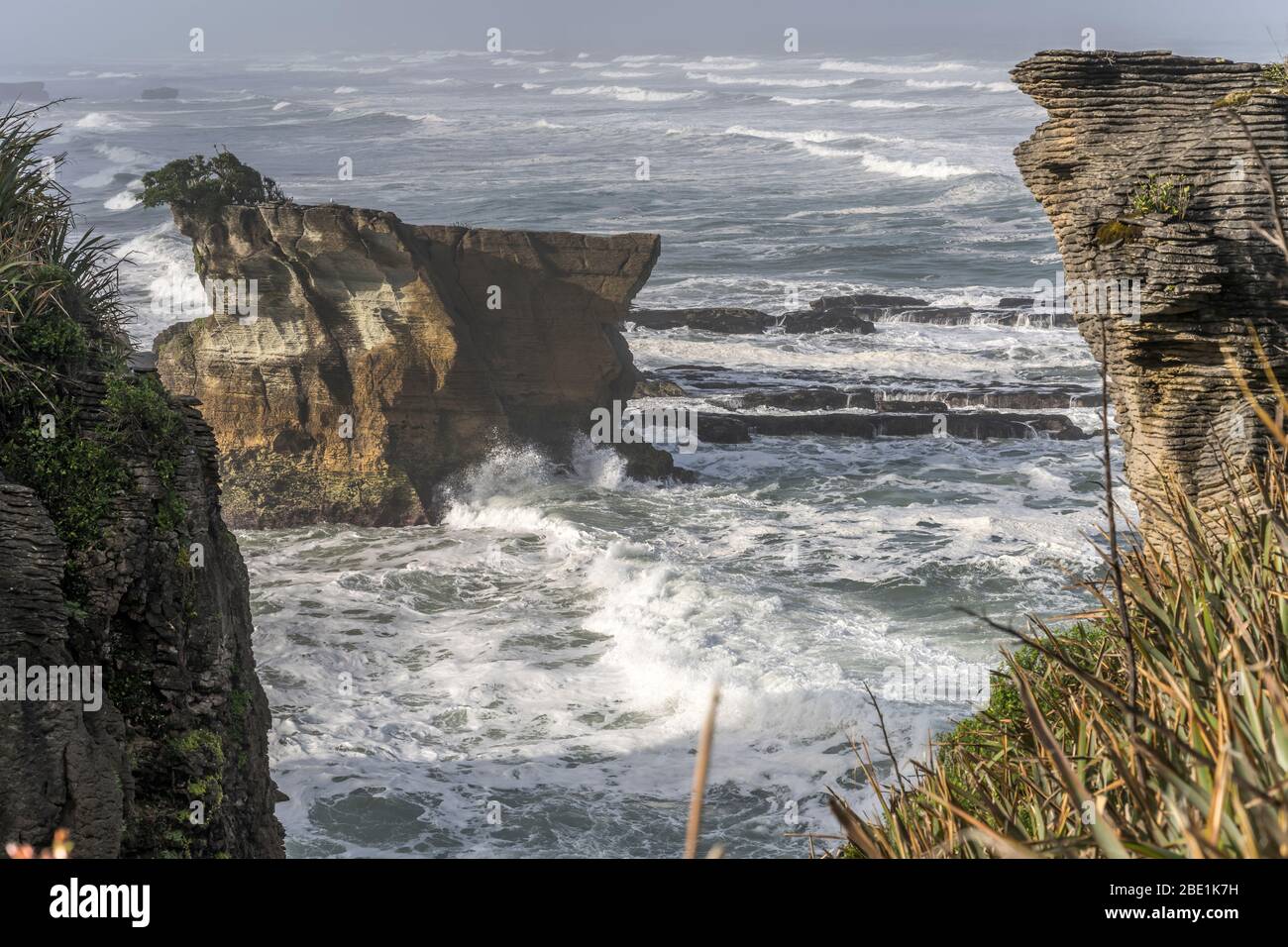 platy worn cliff and Tasman sea waves at shore, shot in bright spring light at Punakaiki, West Coast, South Island, New Zealand Stock Photo