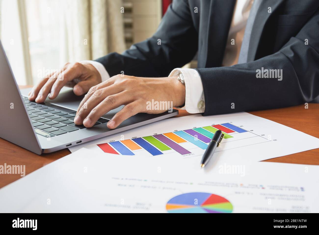 Businessman working on laptop with graph stock chart on table. Stock Photo