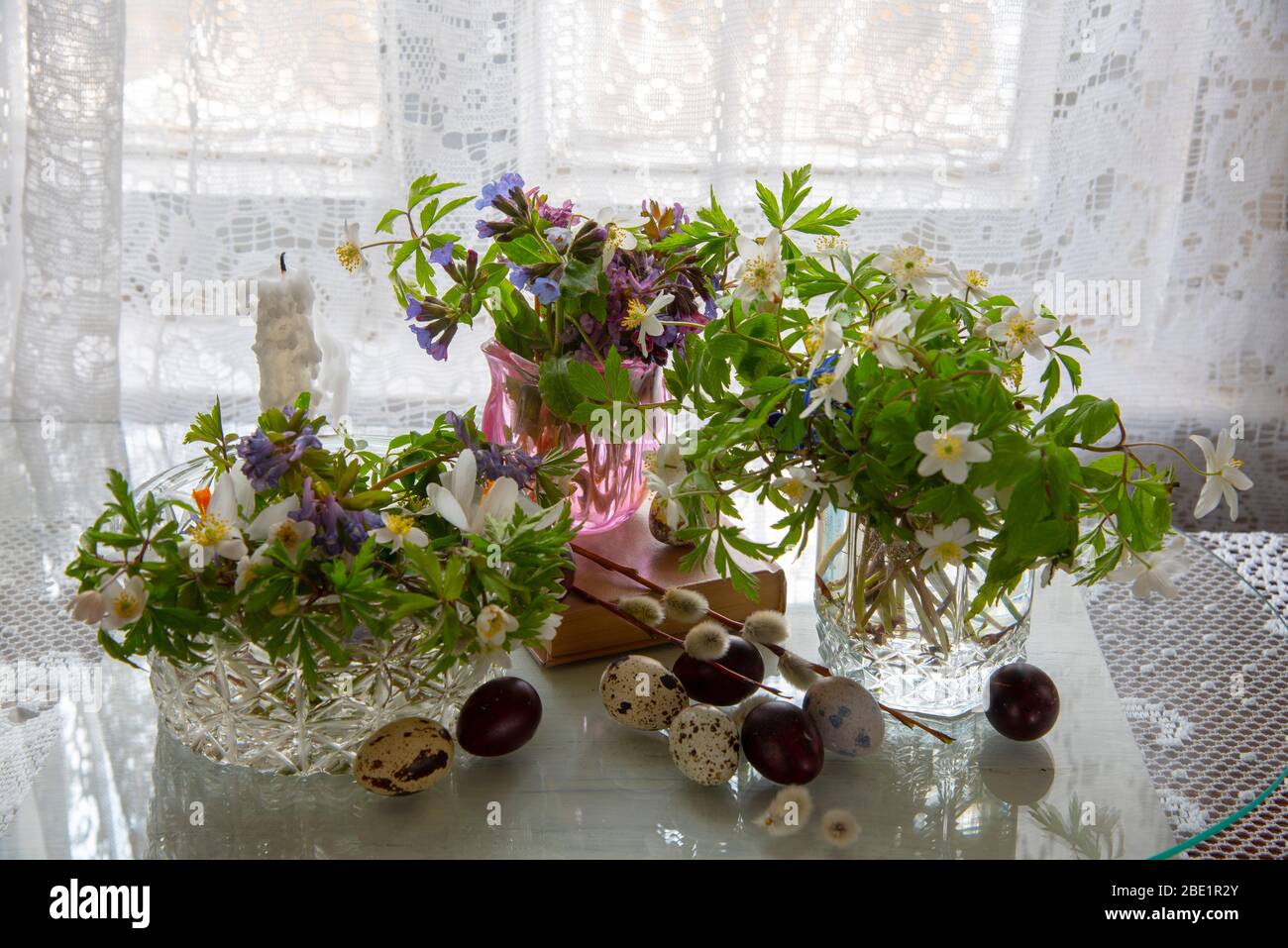 Several vases with spring flowers and Easter eggs on a light background.  Stock Photo