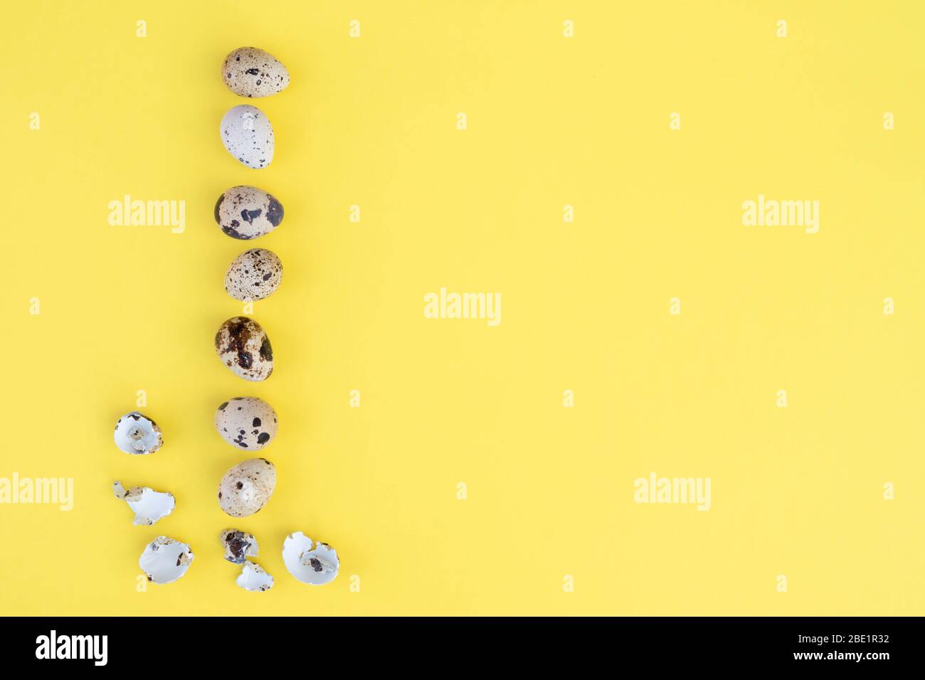 Many small easter eggs on the yellow background. Place for text. Flat lay. Stock Photo