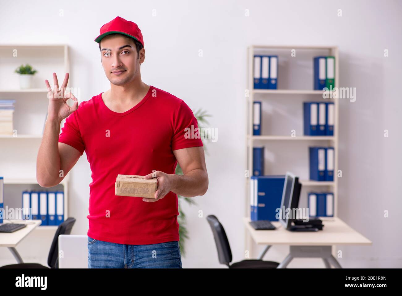 Young courier delivering postbox to the office Stock Photo Alamy