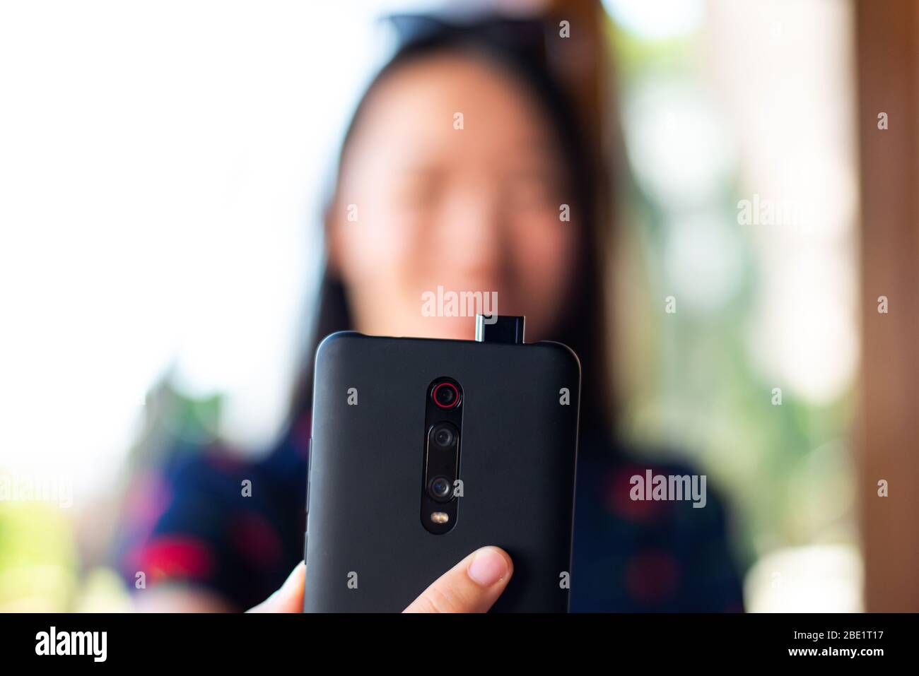Girl taking a selfie with pop up front phone camera Stock Photo