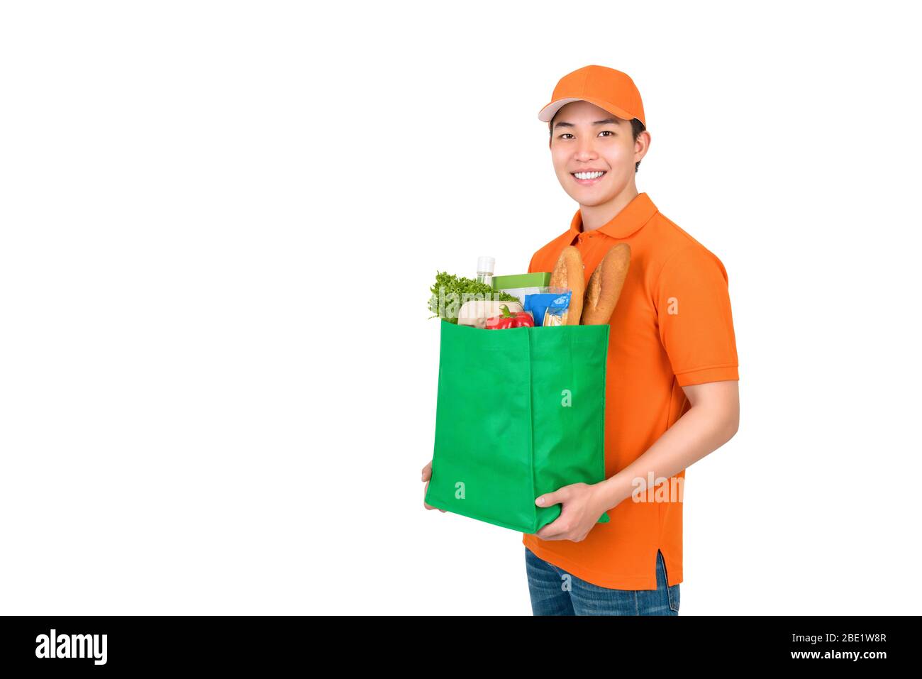 Smiling Asian delivery man carrying groceries shopping bag studio shot isolated on white background Stock Photo