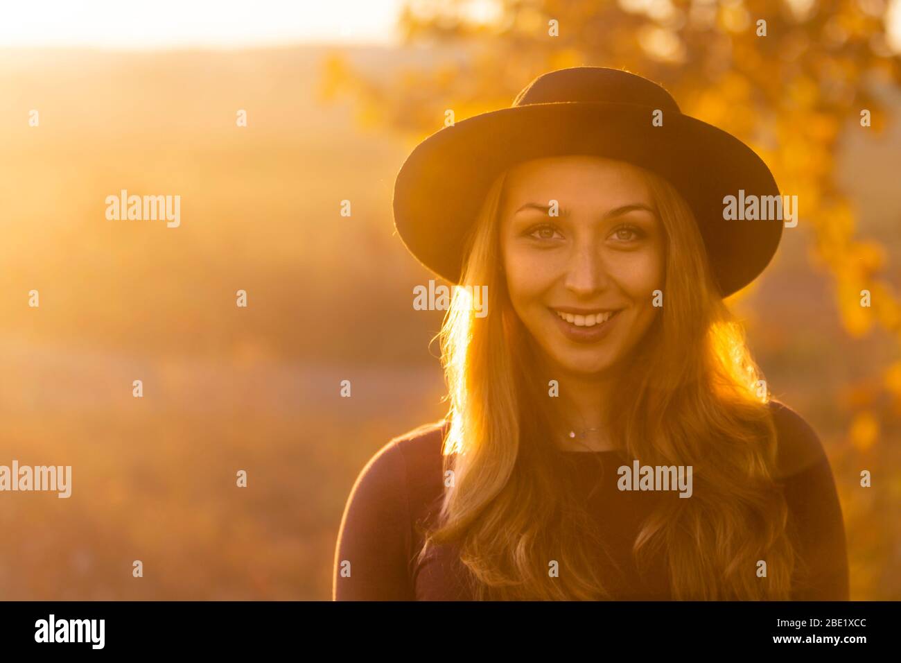 Happy beautiful caucasian girl with long hair in hat smiles, looks at ...