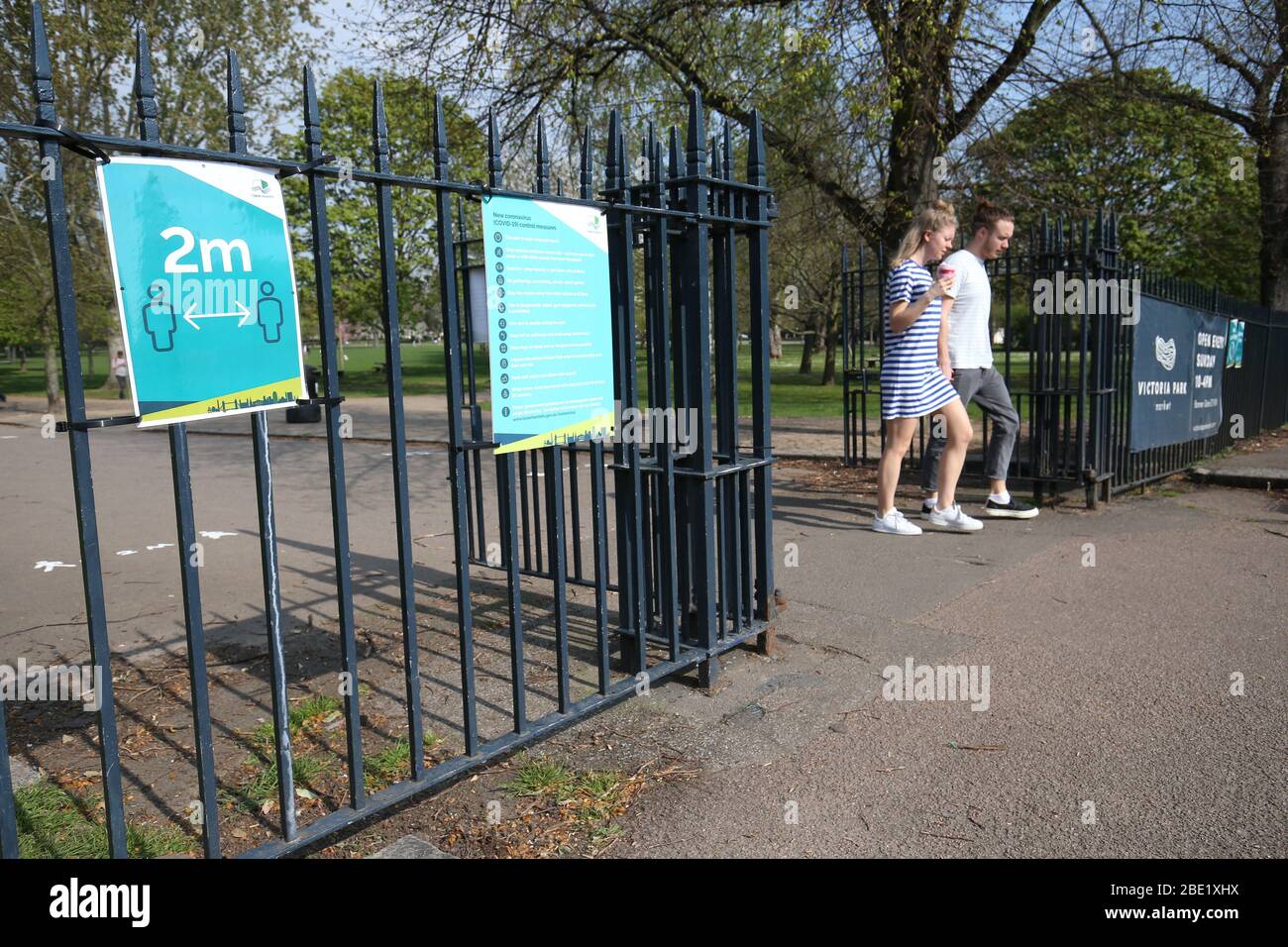 Signs on the gates reminding people to 'social-distance' at Victoria Park, in east London, after it was reopened with reduced opening hours and new control measures in place during the coronavirus outbreak. Stock Photo