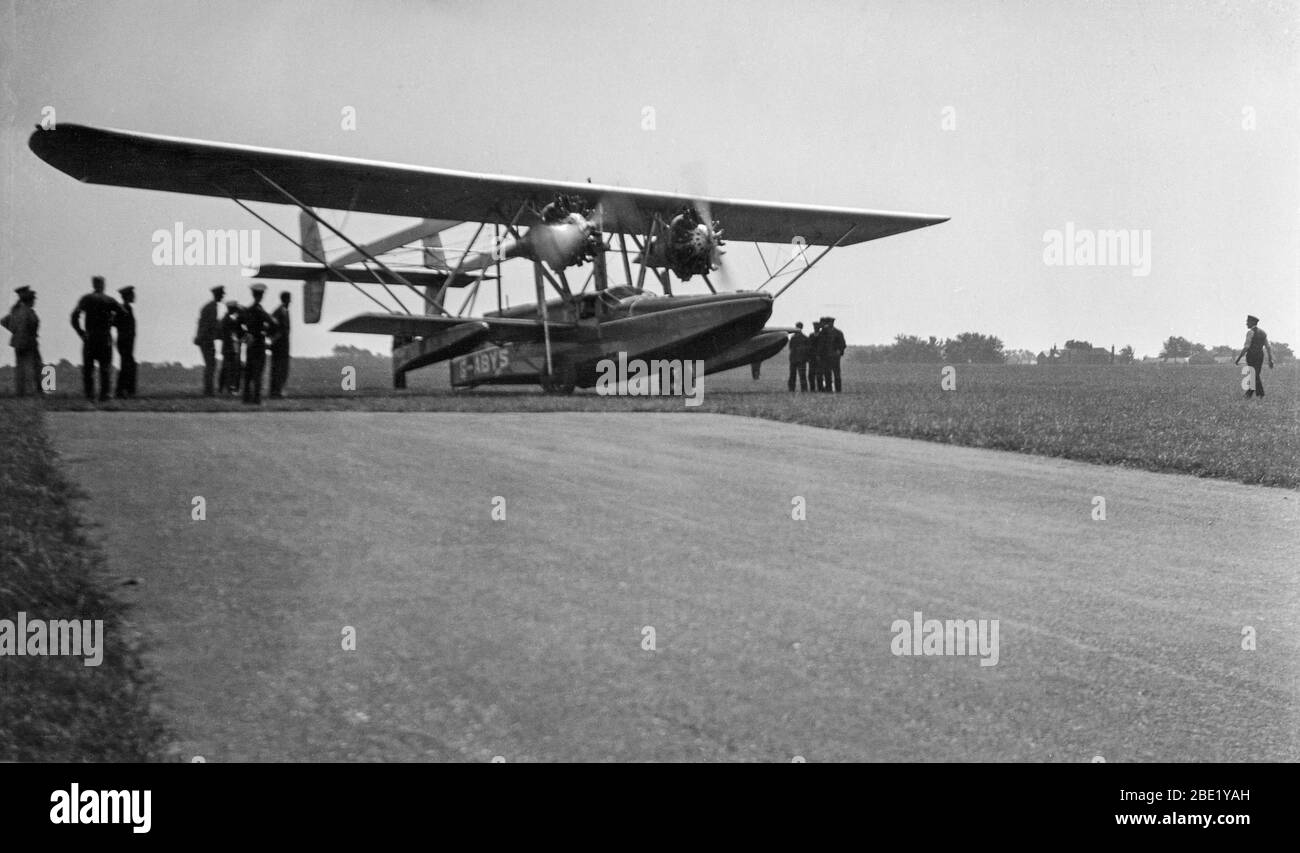 Vintage black and white photograph taken in England in 1933 showing a Sikorsky S-38B Amphibian aircraft, registered in the UK as G-ABYS. Aircraft is parked at the ned of a runway with many soldiers and airmen looking on. Stock Photo