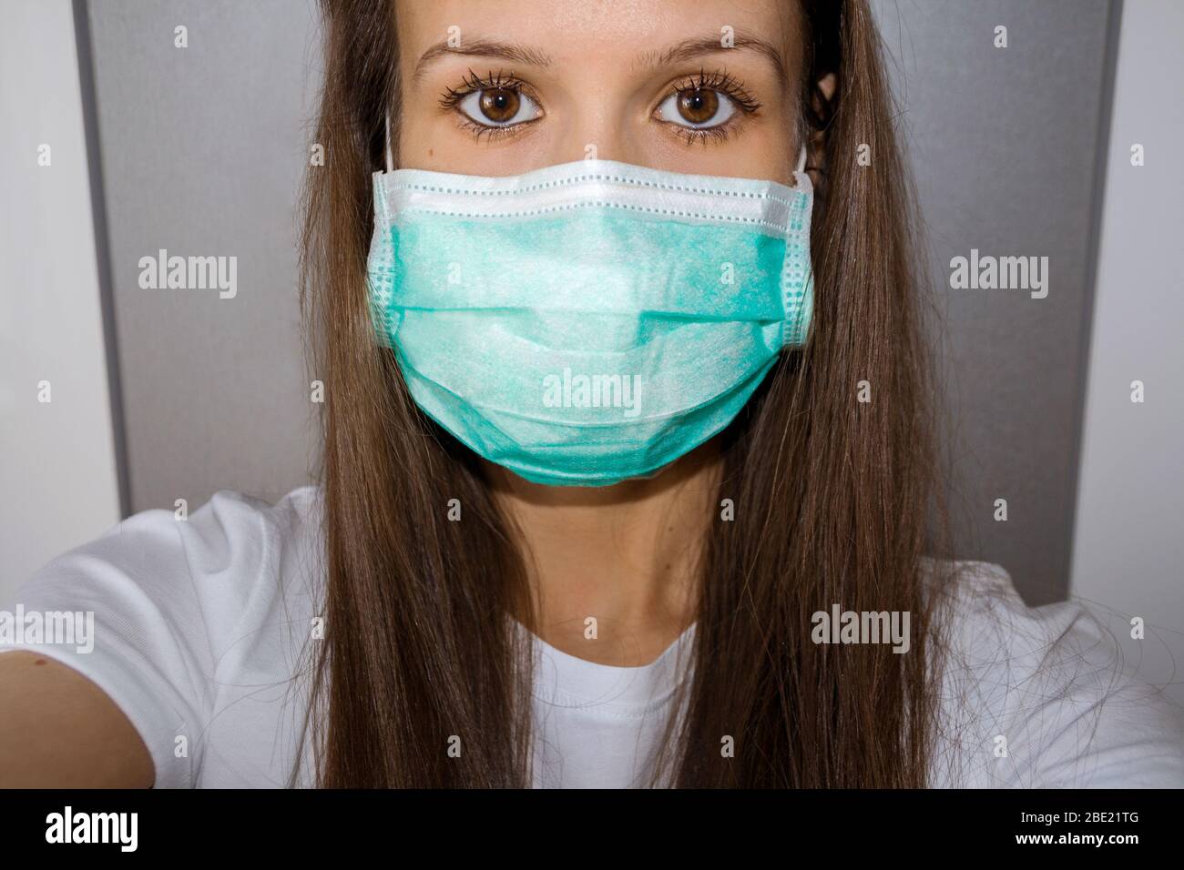 Young Woman is Wearing a Face Mask as a Protection against Covid 19, Corona Virus. Frightened Girl with a Medical Mask - self portrait. Stay At Home C Stock Photo