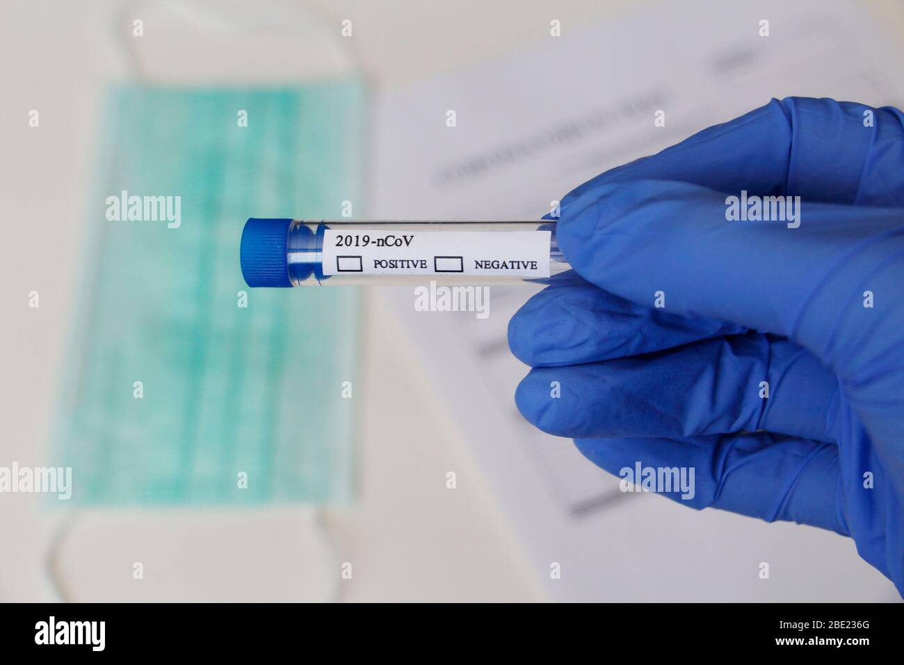 Laboratory test for determination of Coronavirus. Concept. The doctor holds a test tube for analysis. The test tube says POSITIVE and NEGATIVE. On the Stock Photo