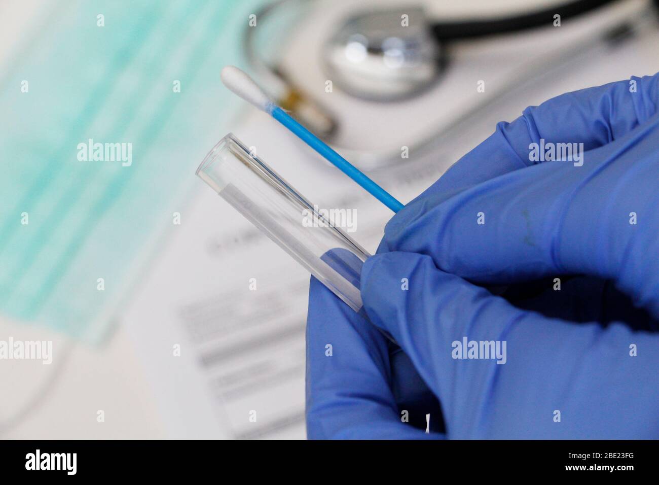 Taking a swab from the oropharynx. Conceptual photography - testing for coronavirus. In the hand is a test tube with a sample of the patient. Tasting Stock Photo